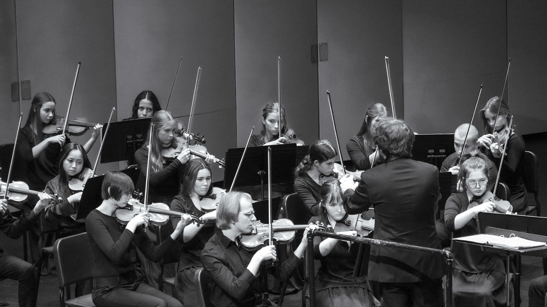 The violin section watches the conductor carefully during the performance.(Photo by Caralyn Price)