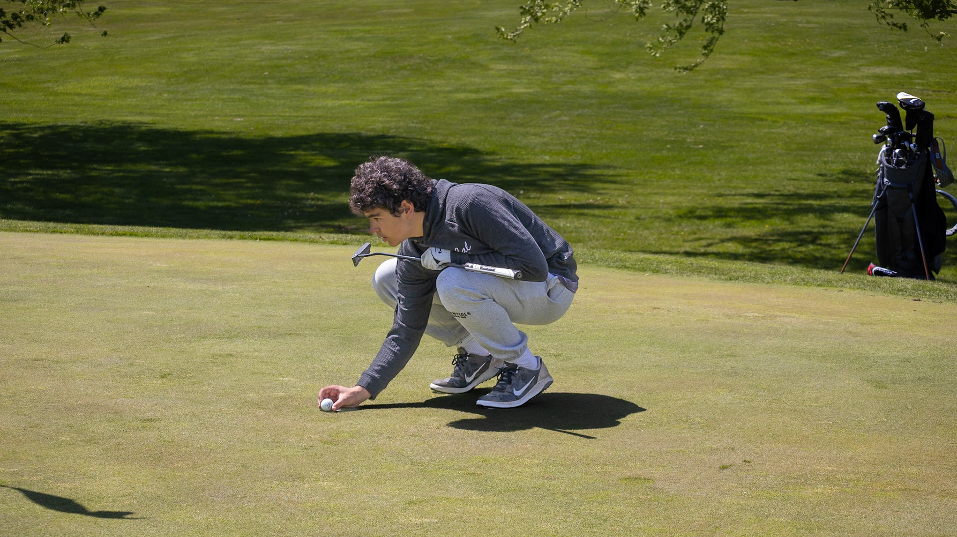Jackson Heffner carefully lines up his putt while reading the green. (Photo by Emma Garza)