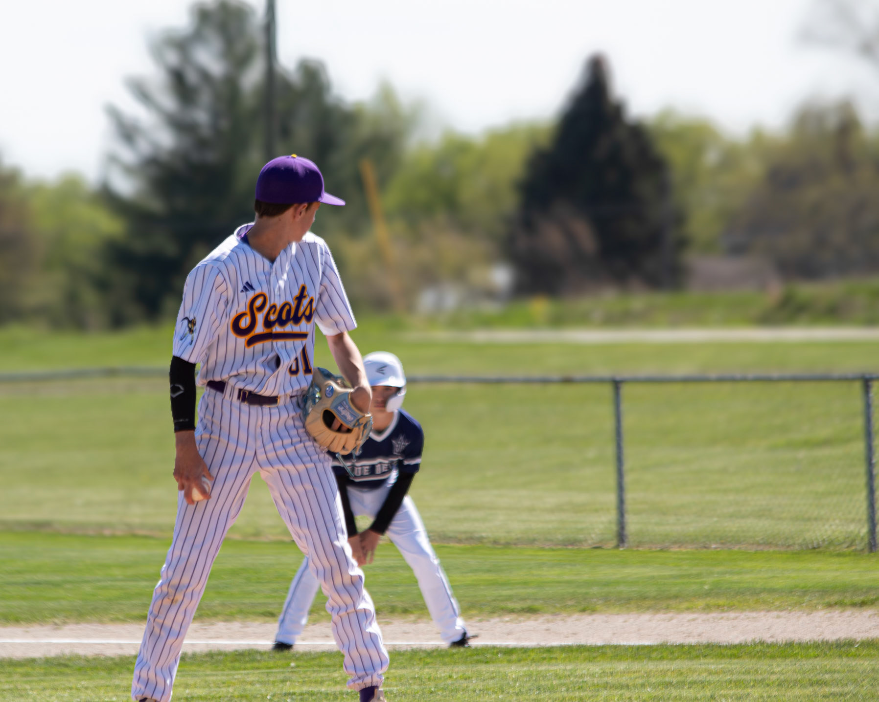 Keeping an eye on the runner behind him, Eli Hileman prepares to pitch while watching for a possible stolen base attempt. (Photo by Elsha Bytwork)