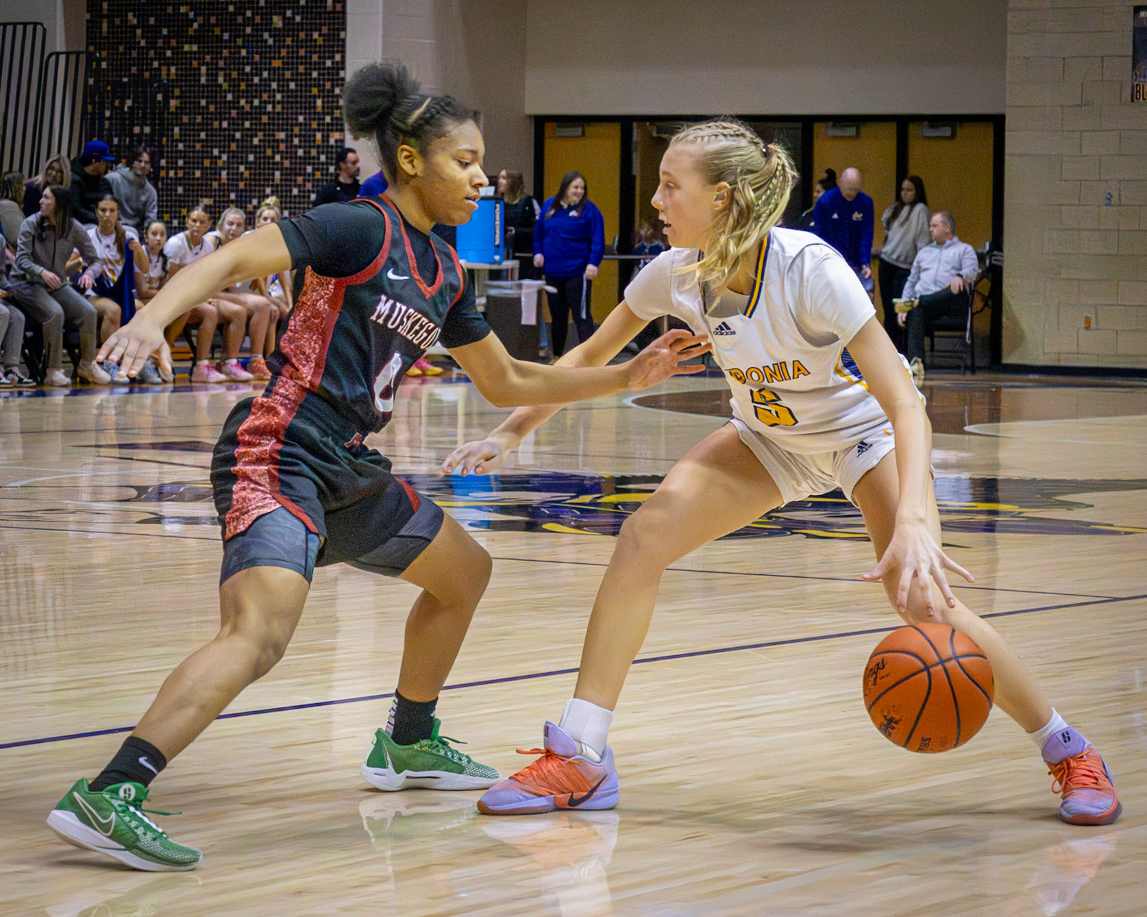 Freshman Reese Abbot takes control in a varsity matchup, dribbling past a defender as the crowd watches from the stands behind them.(Photo by Ava LaBine)