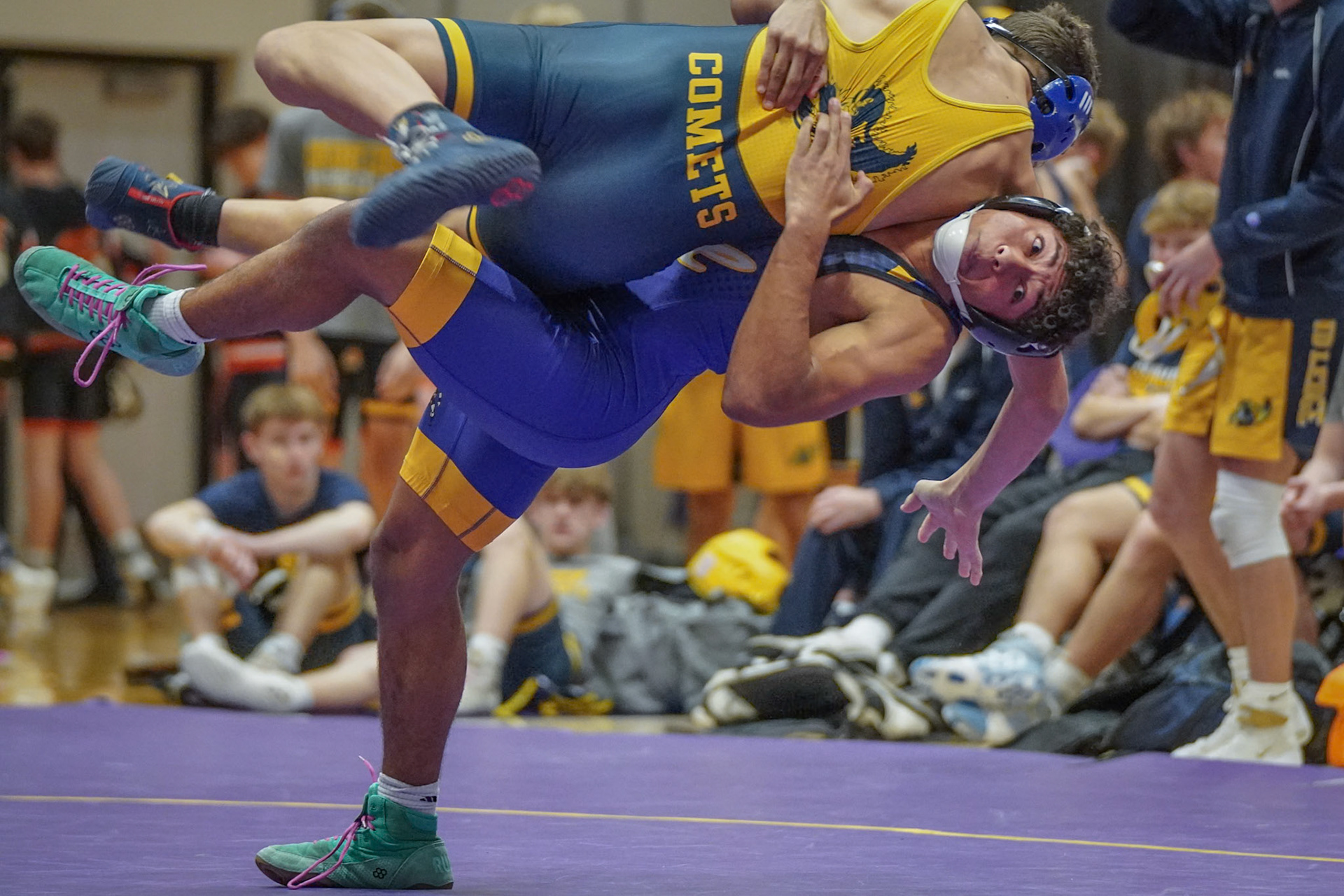 Sophomore Robert Restau drives with a clean takedown, lifting his opponent off his feet, throwing him onto the mat (Photo by Isla Sheely)