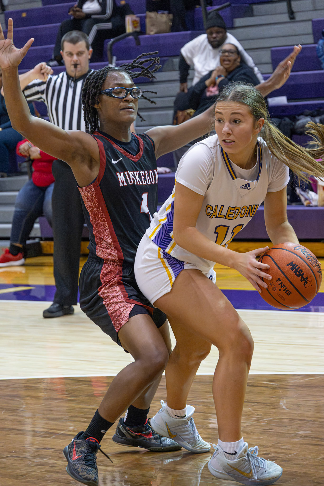 TIGHT DEFENSE Baylee DeVries protects the ball while a Muskegon defender applies pressure in varsity action. (Photo by Taya Penoes)