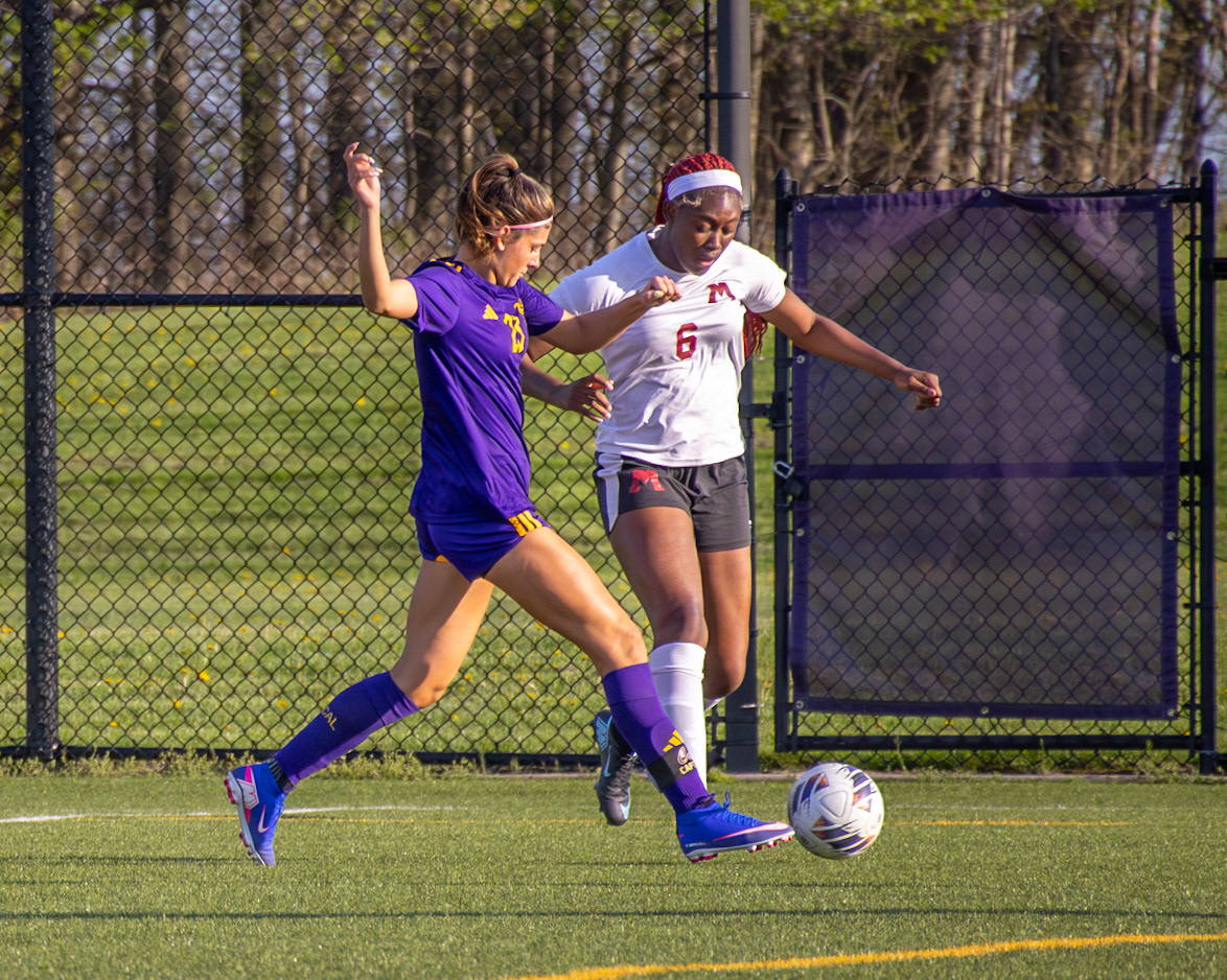 Fierce, Kayla Briseno strikes the ball while shielding it from her defender, refusing to give up possession. (Photo by Aibree Akers)