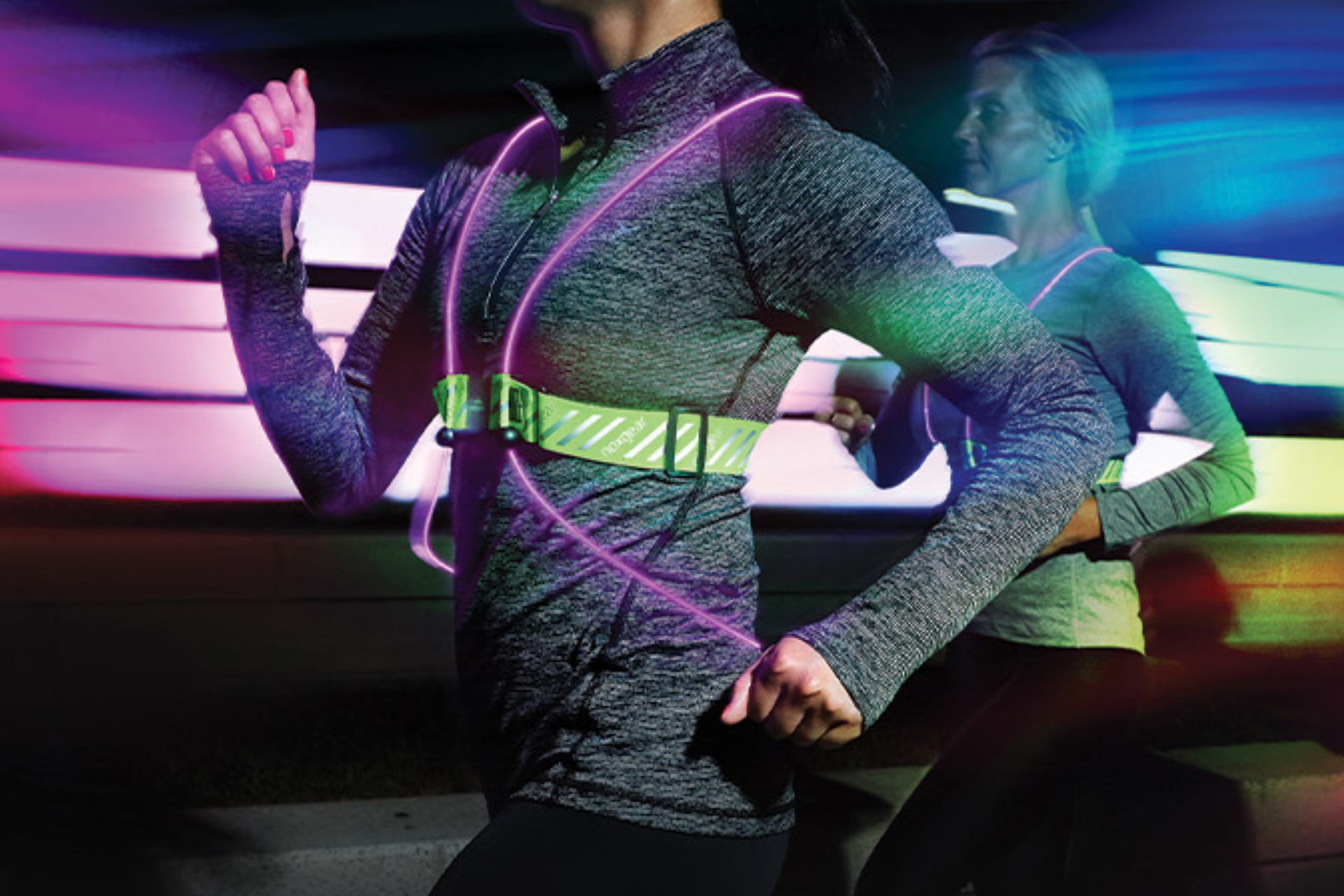 Two women running through a dark tunnel with reflective LED light vests on