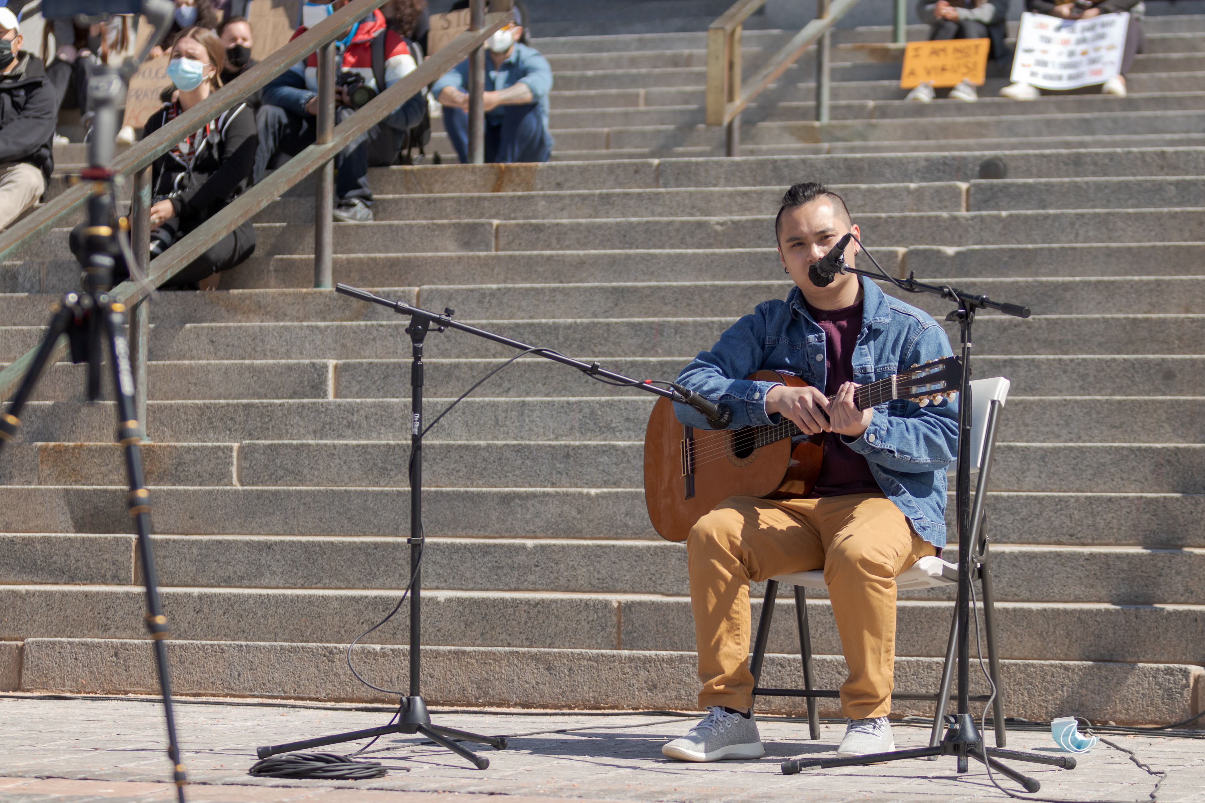 Ben Nguyen speaks to the crowd outside the Colorado State Capitol during a protest March 27, before performing an original song about the pain of losing a loved one. Nguyen learned to play guitar during quarantine and came to the protest "to grieve... and to kind of share that vulnerability, and to... be with my community".