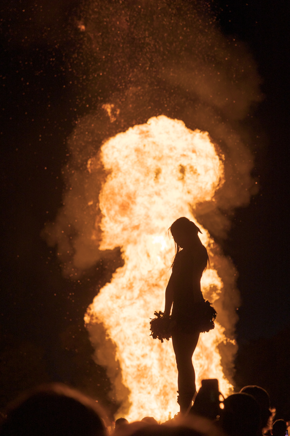 A Colorado State University cheerleader performs a stunt in front of a bonfire during Friday Night Lights Oct. 14, 2022.