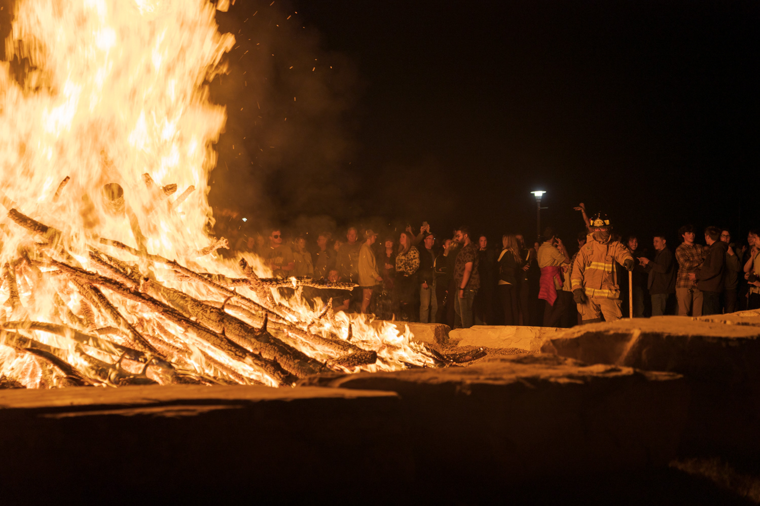 A Poudre Fire volunteer firefighter stands next to a bonfire outside the Lory Student Center during Friday Night Lights Oct. 14, 2022.