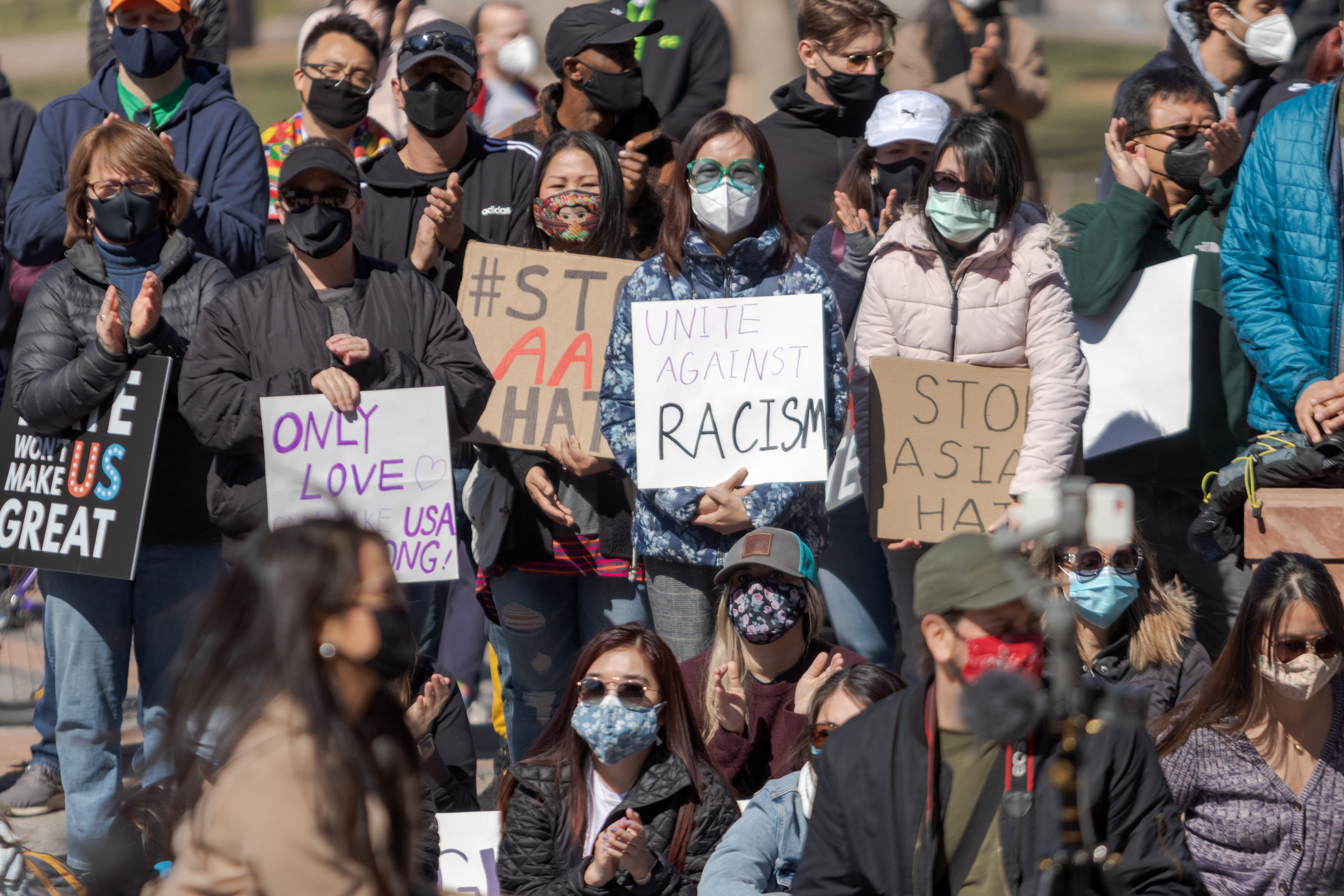 Protesters hold signs outside the Colorado State Capitol March 27. The protest featured speeches, poetry, and music from the Asian-American and Pacific Islander community.