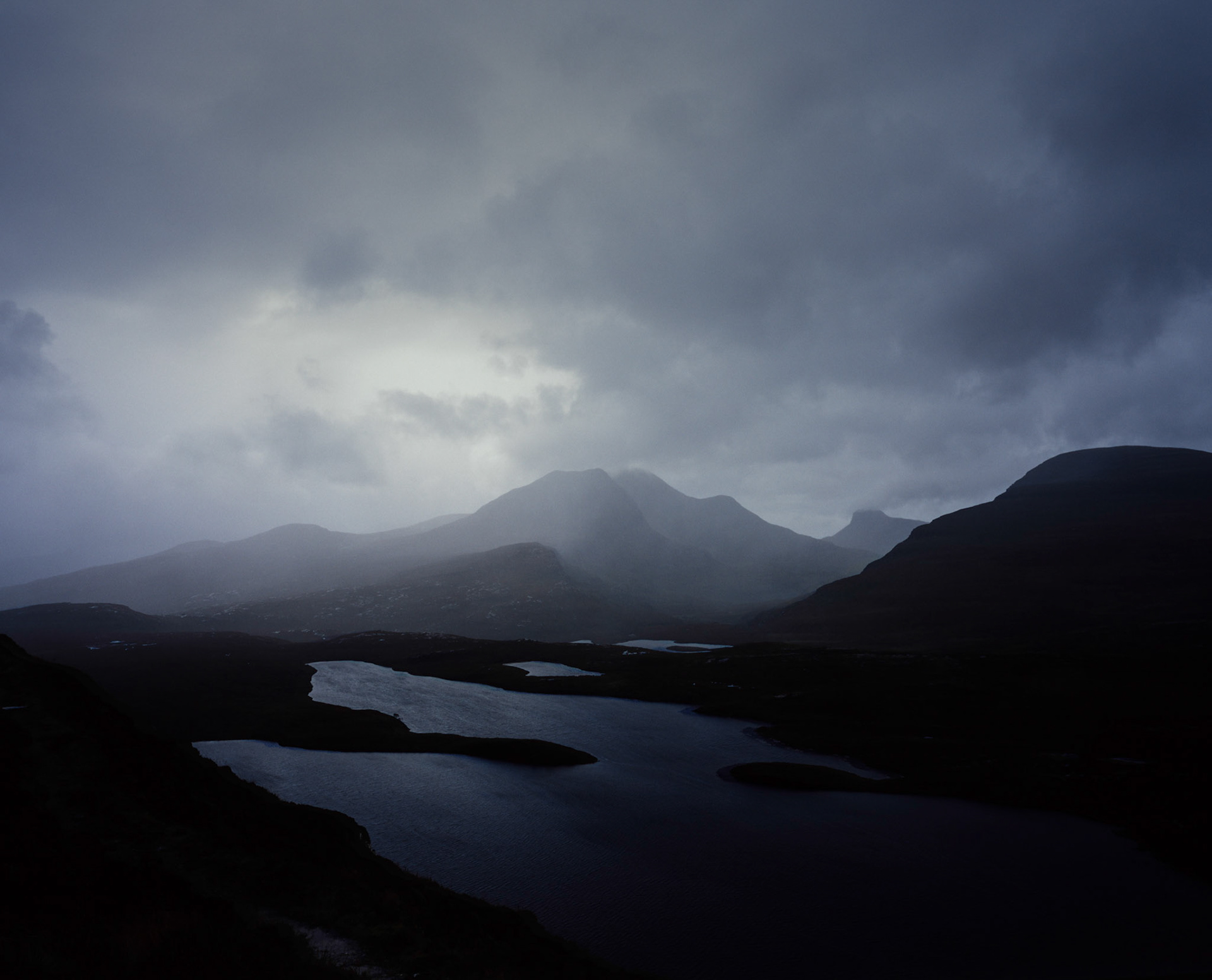 Dramatic storm clouds over mountains and lochs in Scottish Highlands, Scotland