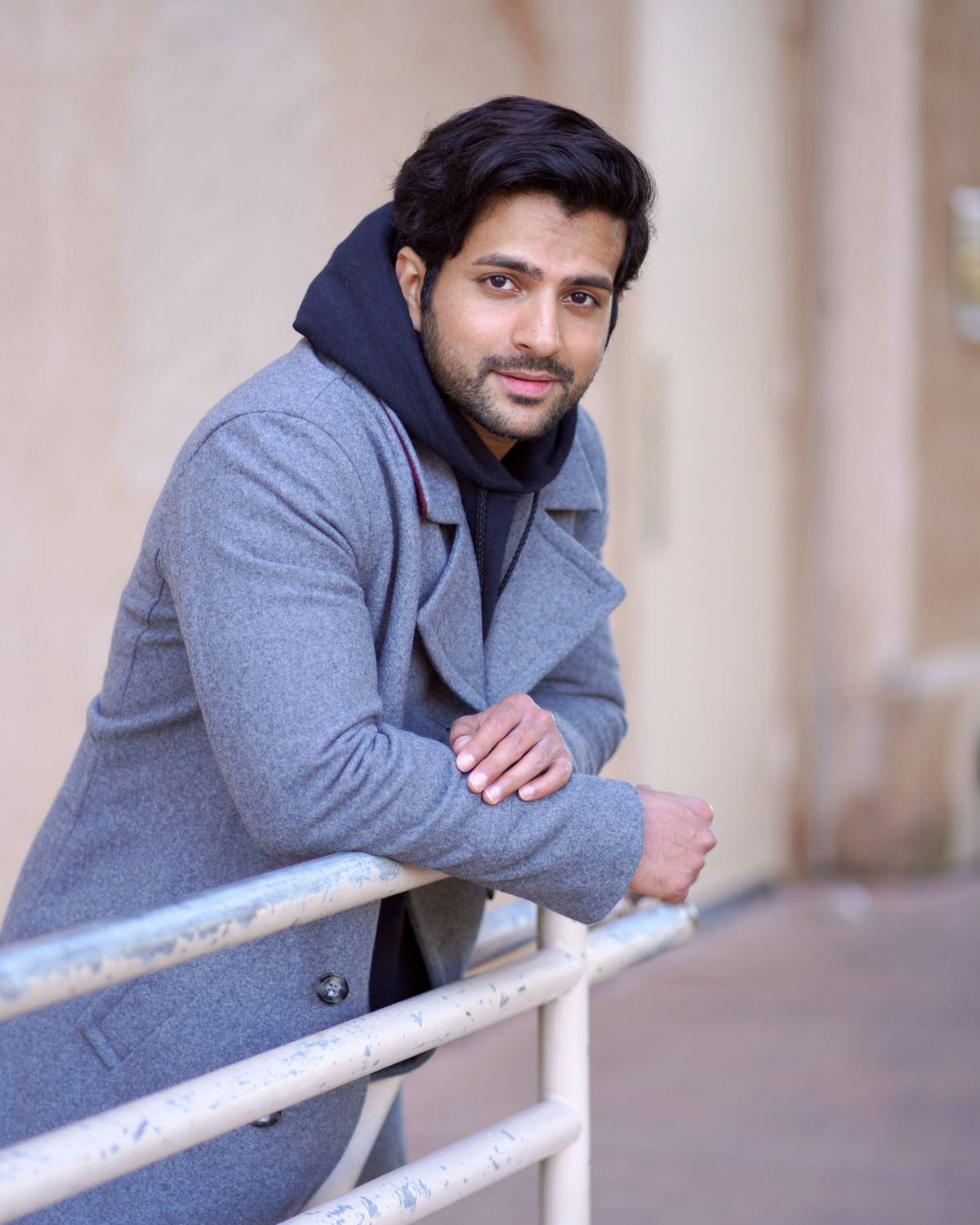 Man in grey coat leaning on a handrail outdoors