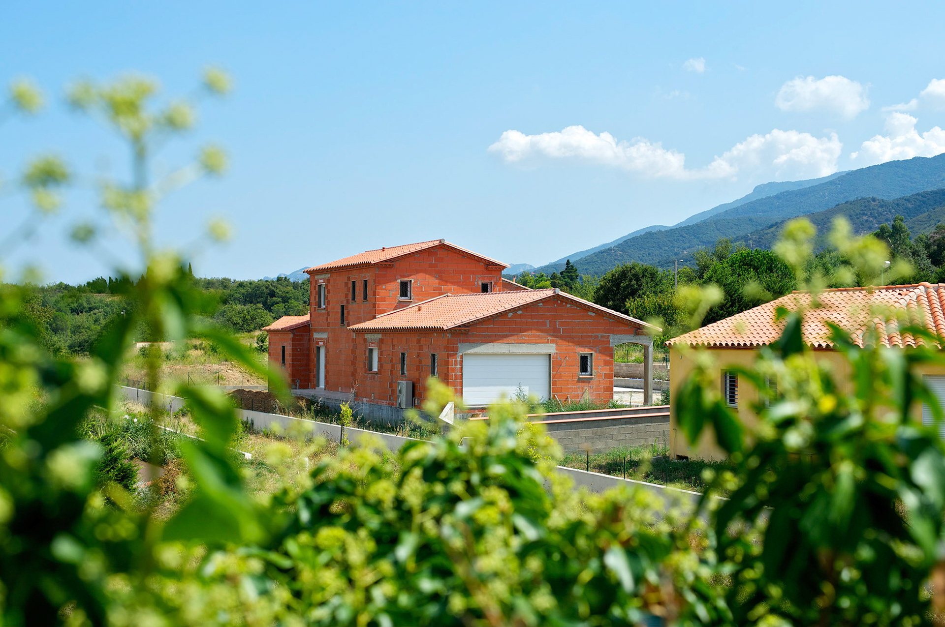 Maison en construction. Montesquieu des Albères,   Pyrénées Orientales, France. Feuillage flou au premier plan.