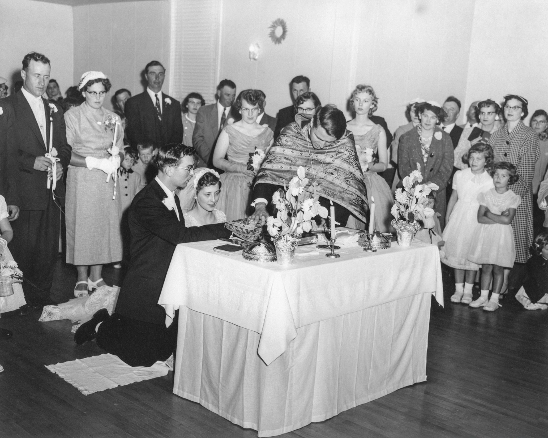 L to R: George Kachuk and Lena [Shewchuk] Tatarin (background), John Huculak, Kathleen Shewchuk (kneeling), Rev Dmytro Luchak. Evelyn Shewchuk, Julia Kocak (obscured), Pat Proniuk behind Reverend. Far background John Tatarin (spouse to Lena) Metro Romanko (obsured). Nettie [Shewchuk] Megley adjacent Pat P. with daughters Lorna and Olli (sisters to flower girl Julia not pictured)