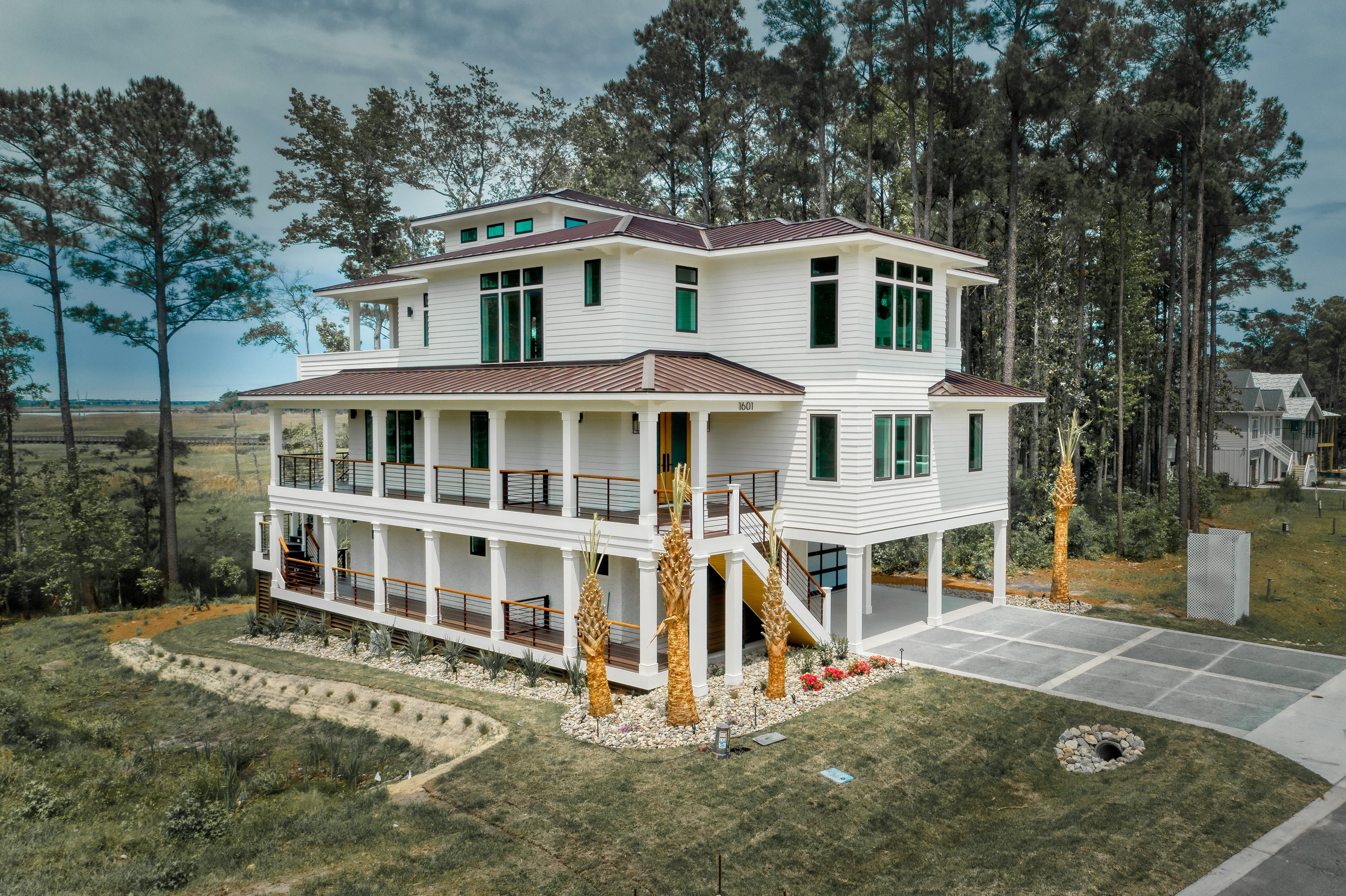 Elevated custom coastal home in Wilmington, NC featuring multiple wraparound porches, hurricane-rated windows, standing seam metal roofing, and panoramic river views.