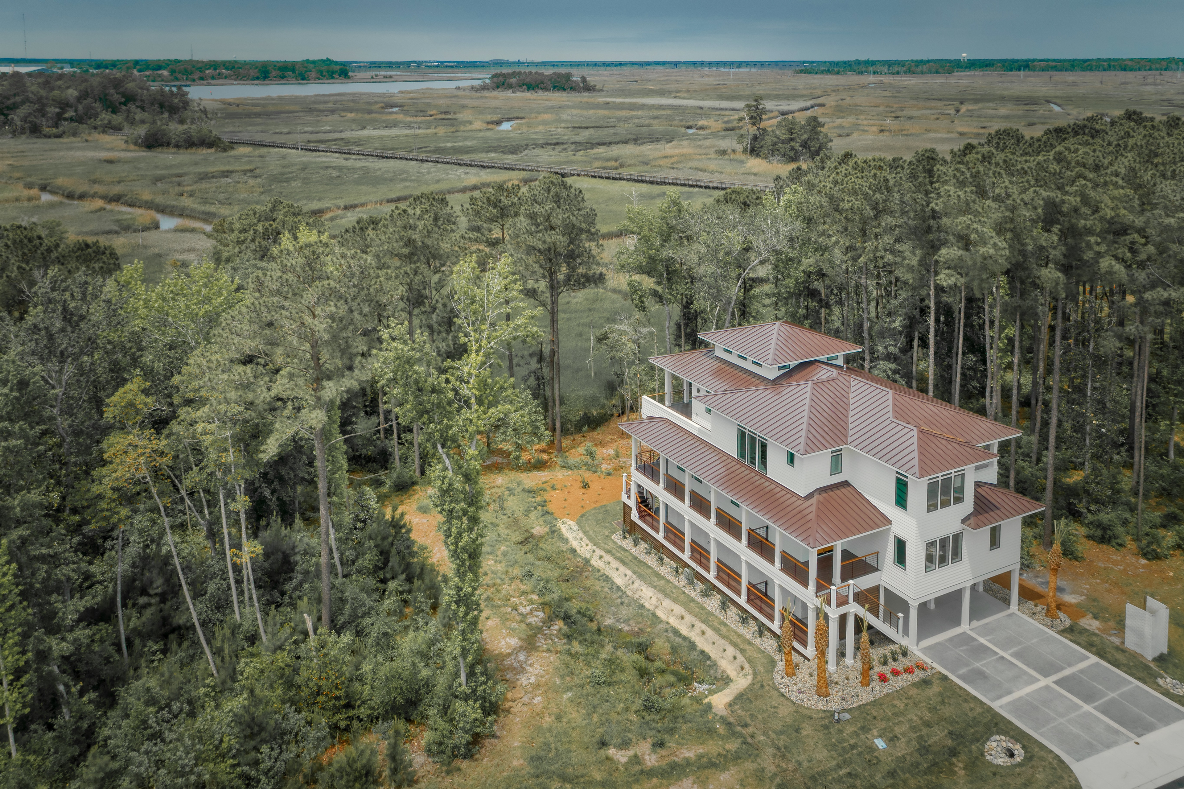 Aerial view of a custom marshfront home showcasing elevated construction, private natural surroundings, and seamless integration with the North Carolina coastal landscape.