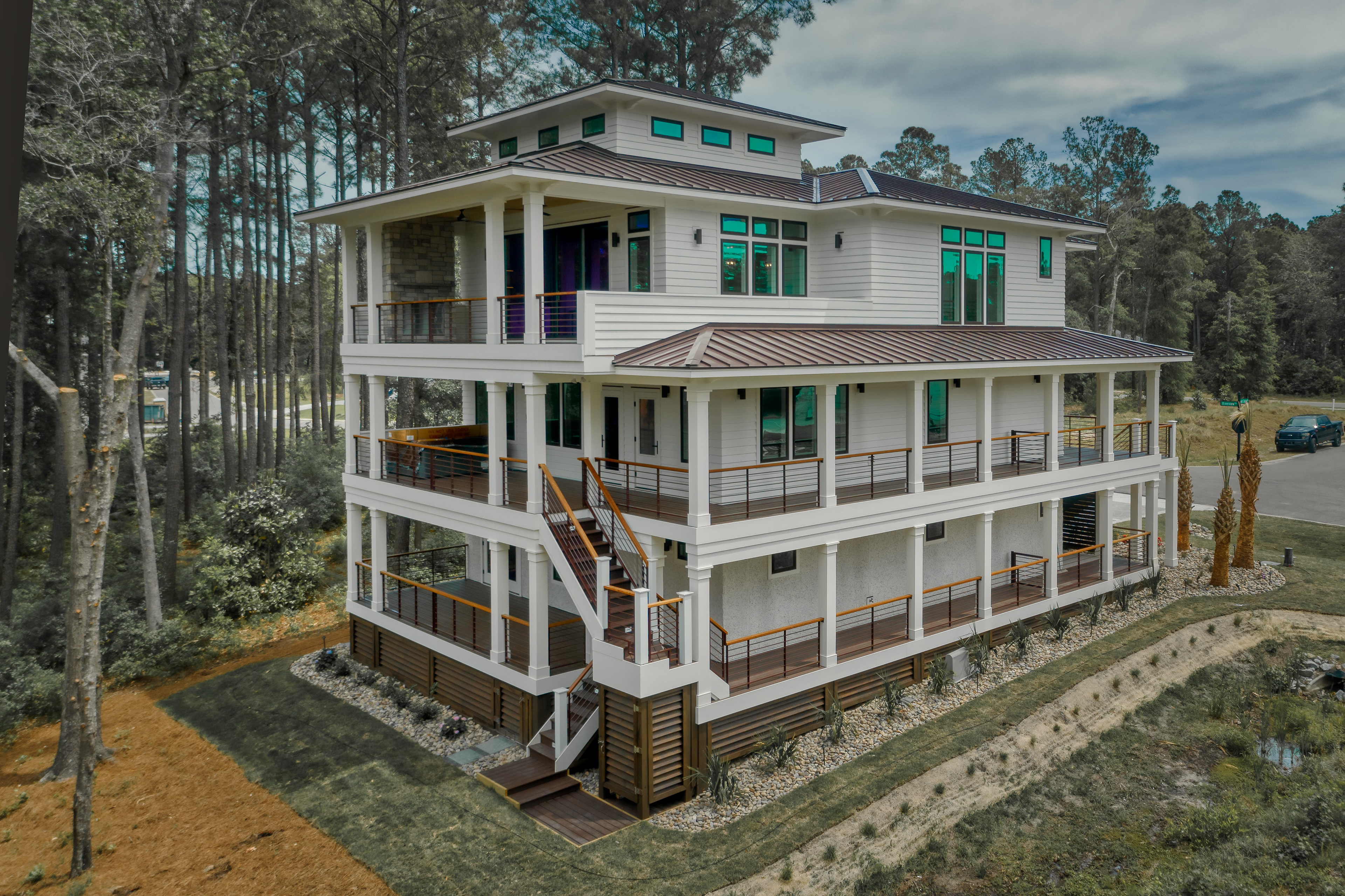 Luxury waterfront residence with expansive outdoor living spaces, modern coastal architecture, cable railing systems, and covered porches designed for year-round entertaining.
