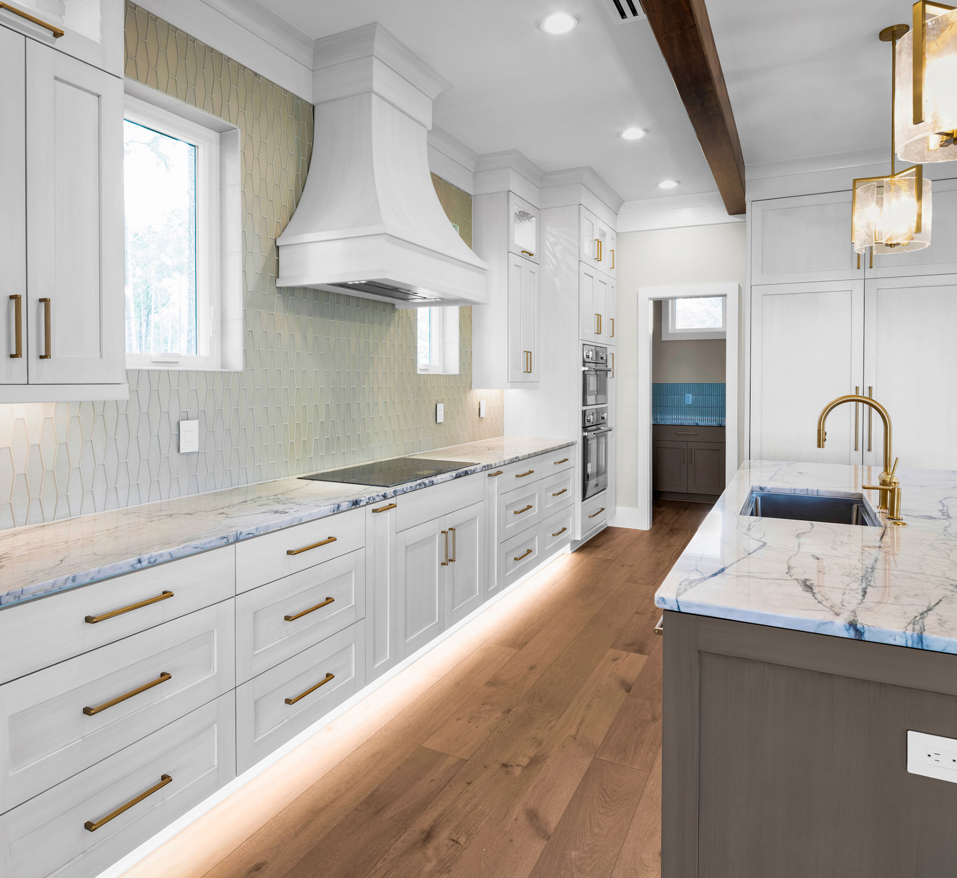 Luxury chef’s kitchen with custom cabinetry, quartz countertops, statement range hood, wood ceiling beams, and oversized island for entertaining.