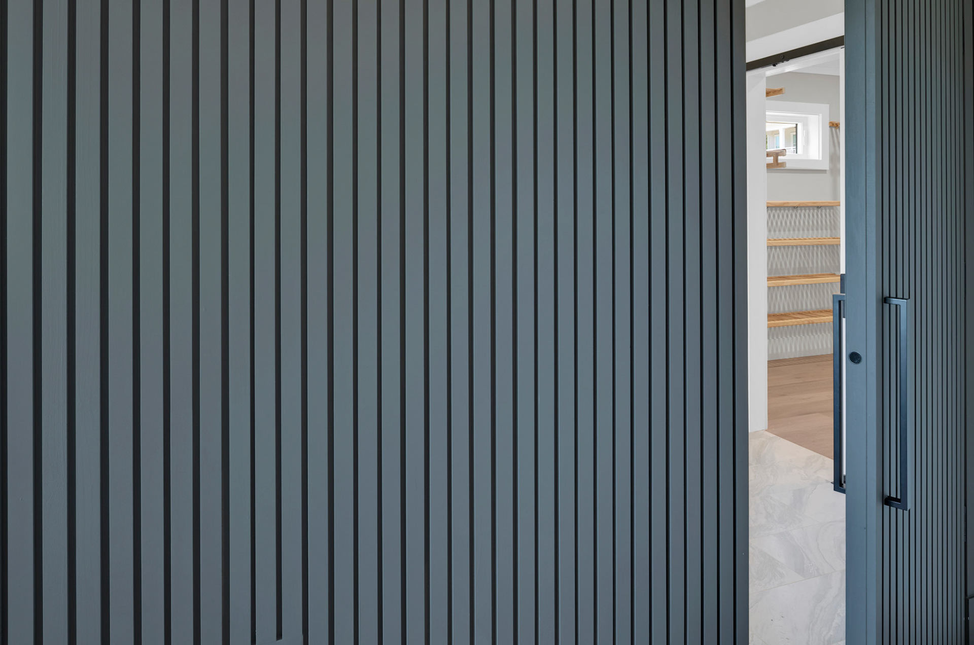 Hidden door with custom vertical wood detail opens to reveal private bath and walk-in closet.