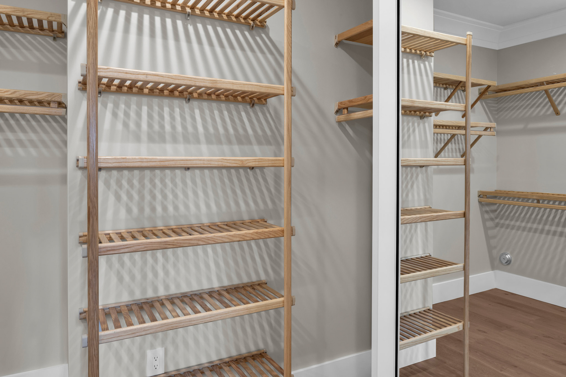 Custom walk-in closet with open wood shelving system, boutique-inspired organization, and premium storage solutions for luxury coastal living.