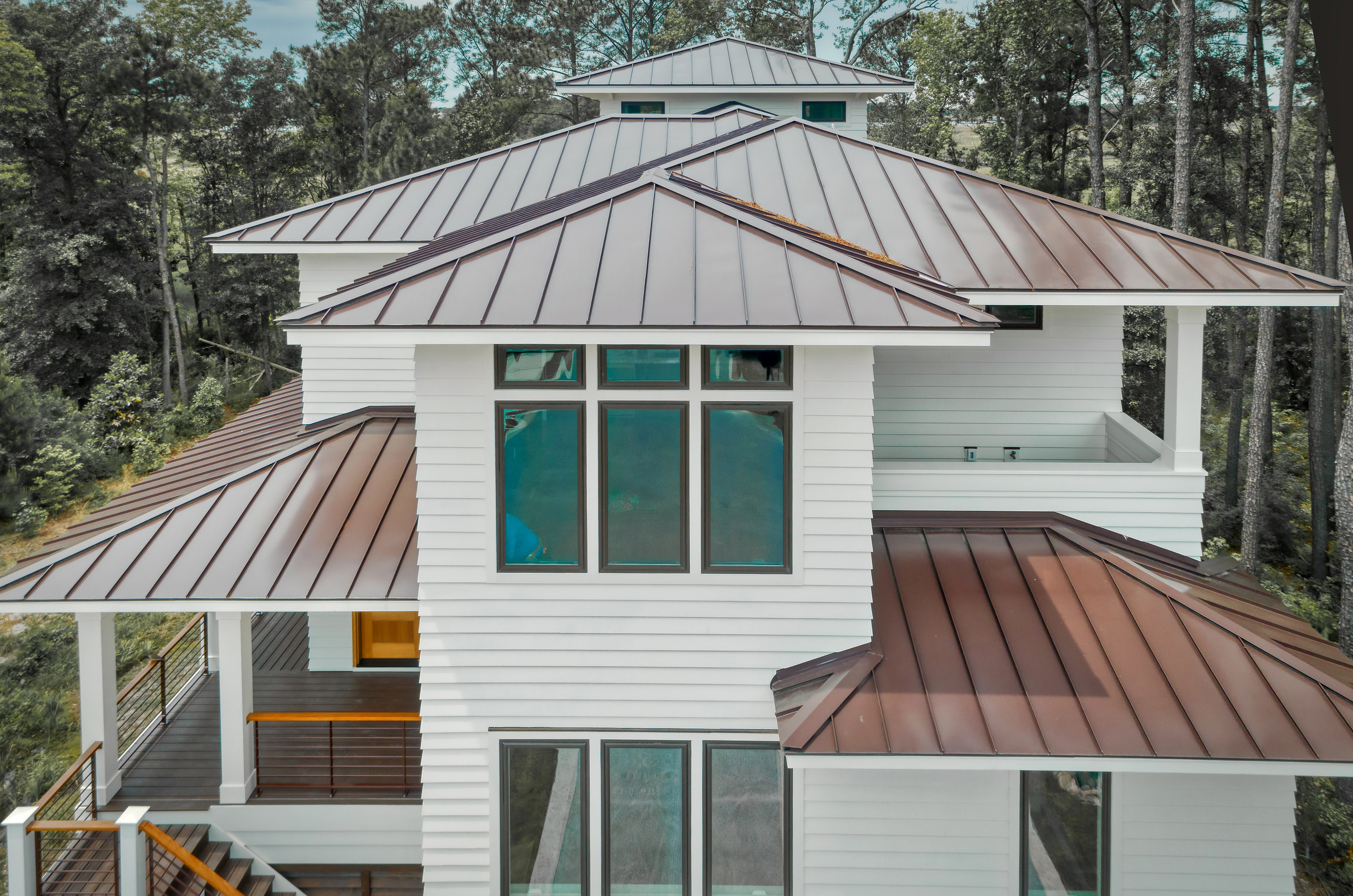 Architectural roofline detail featuring standing seam metal roofing, clerestory windows, fiber cement siding, and energy-efficient coastal home design built for waterfront durability.