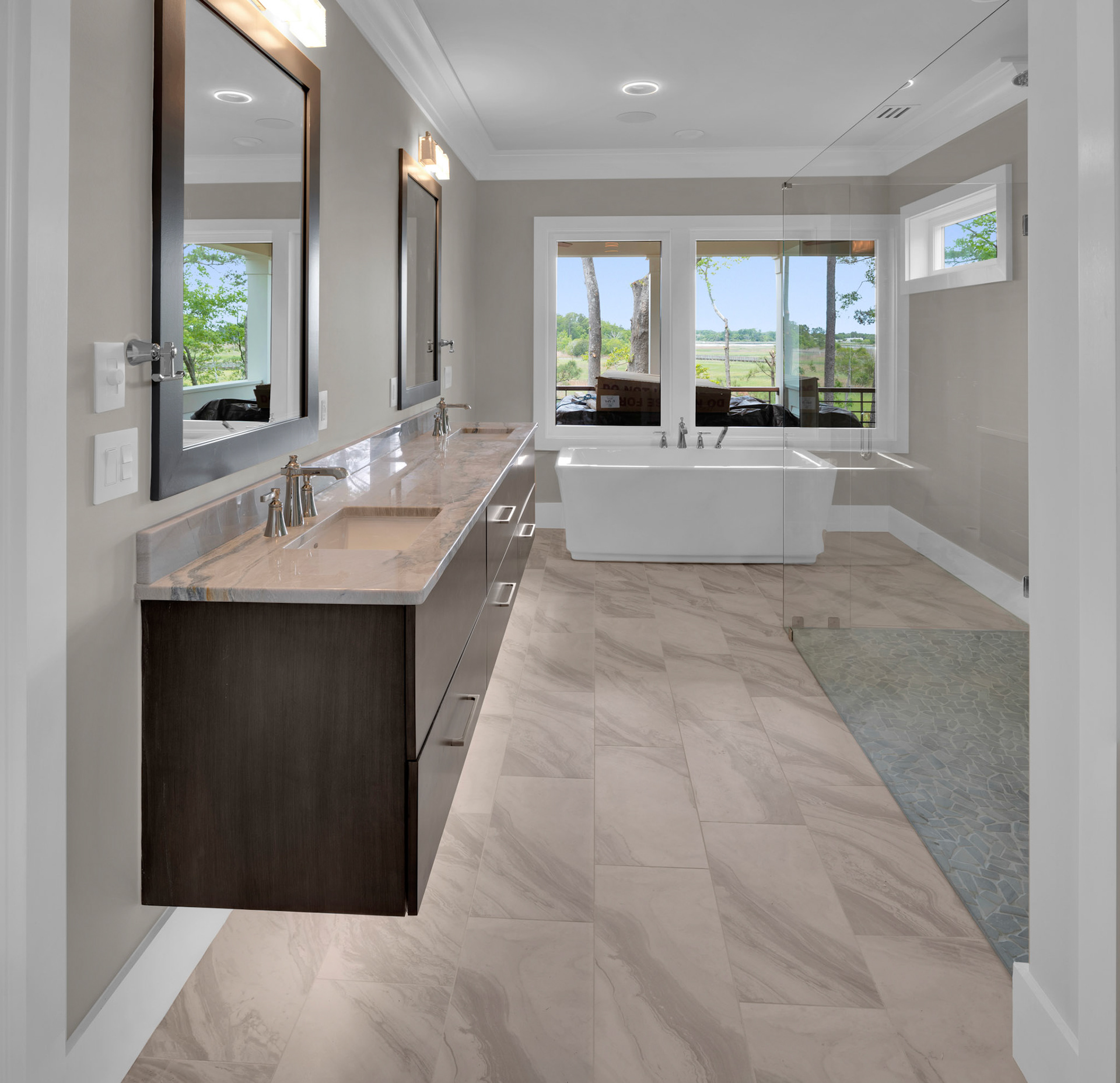 Spa-inspired primary bathroom with floating dual vanity, freestanding soaking tub, oversized walk-in shower, and luxury tile flooring.