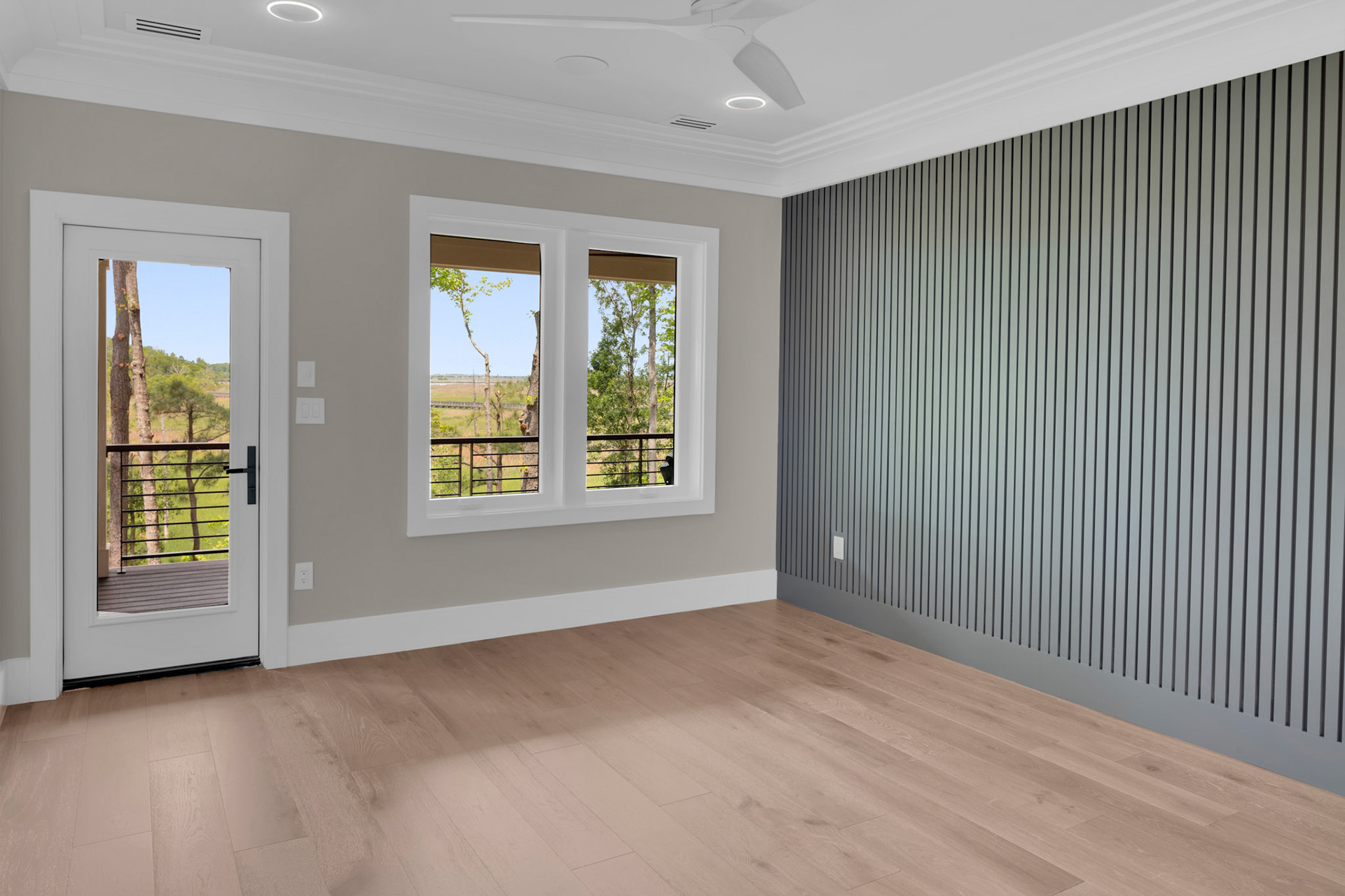 Private bedroom retreat with textured accent wall, oversized windows, and direct access to outdoor living spaces overlooking the coastal landscape.