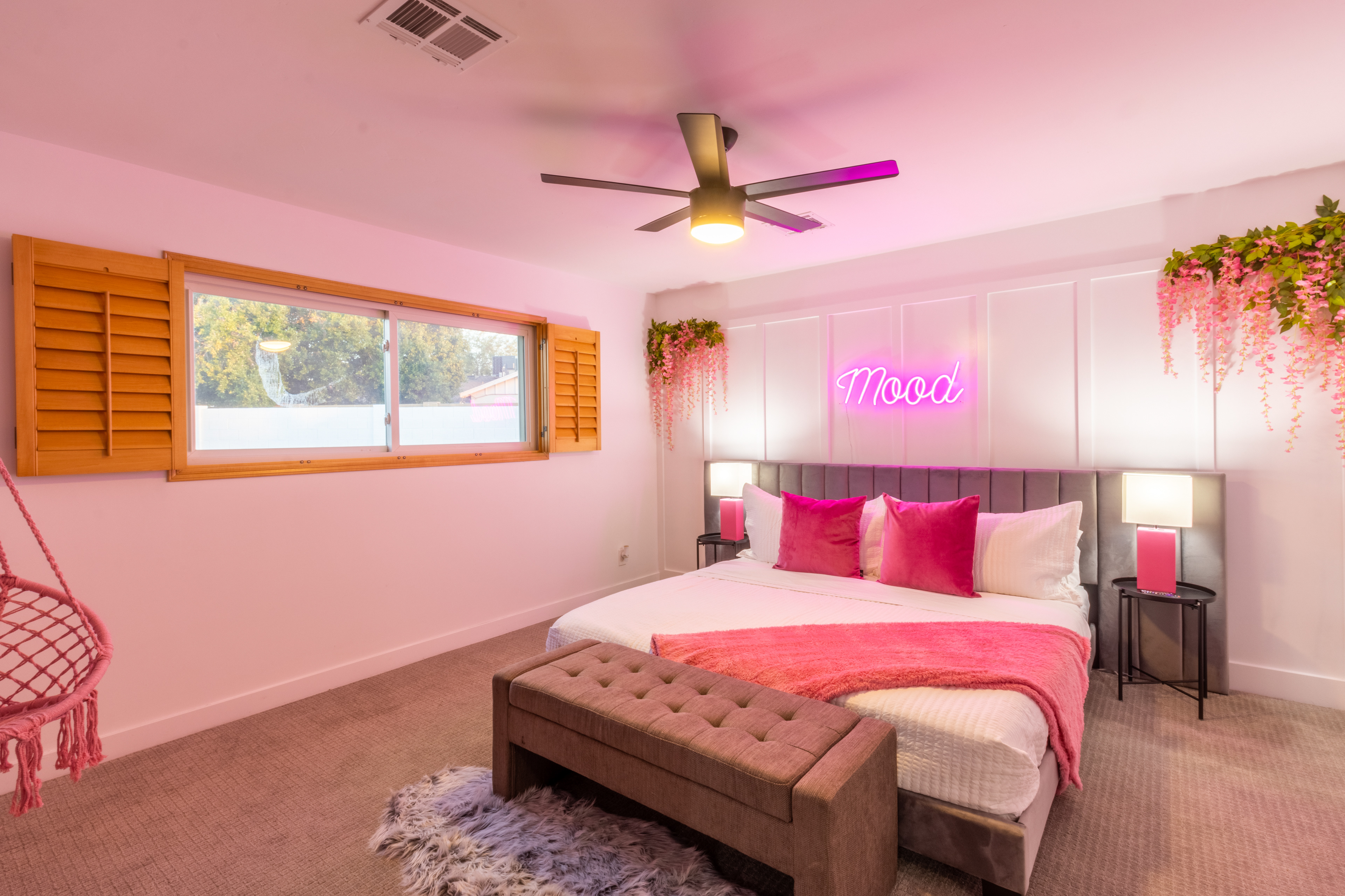 Pink bedroom with neon sign and ceiling fan