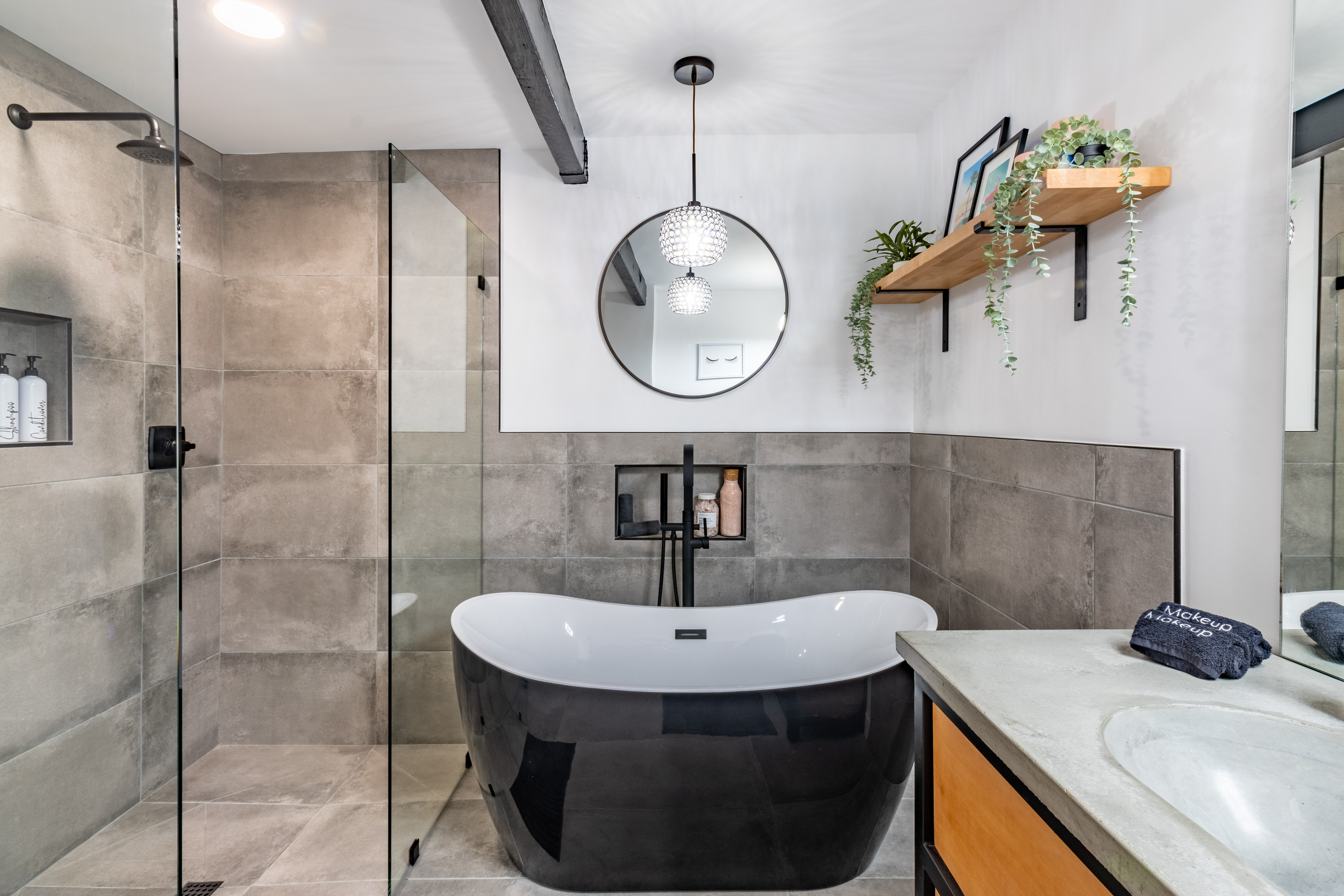 Freestanding black tub beside a glass shower