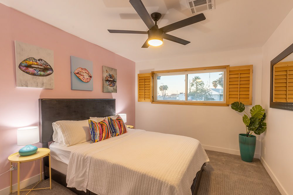 Bedroom with pink accent wall and ceiling fan