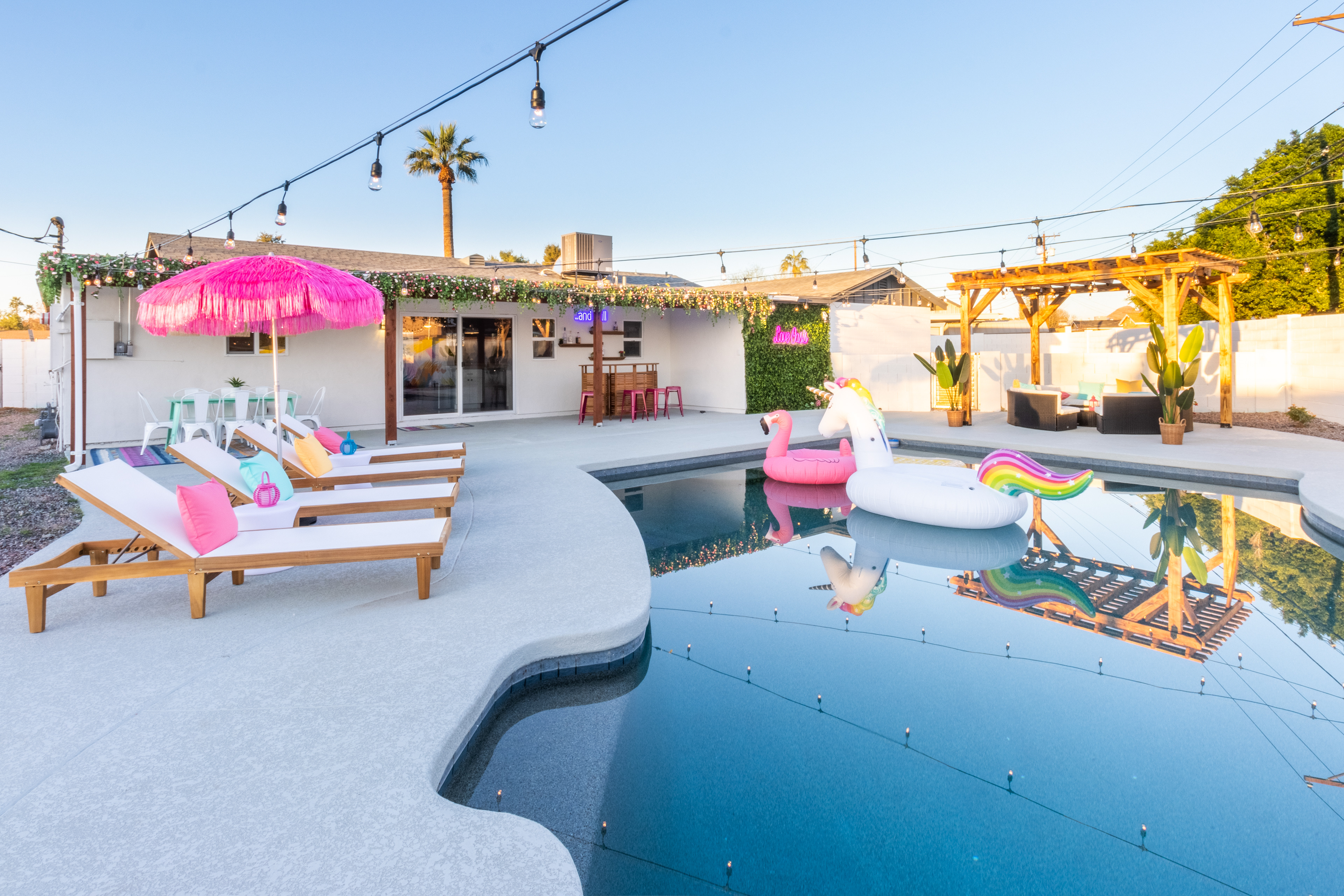 Curved pool deck with lounge chairs and pink umbrella