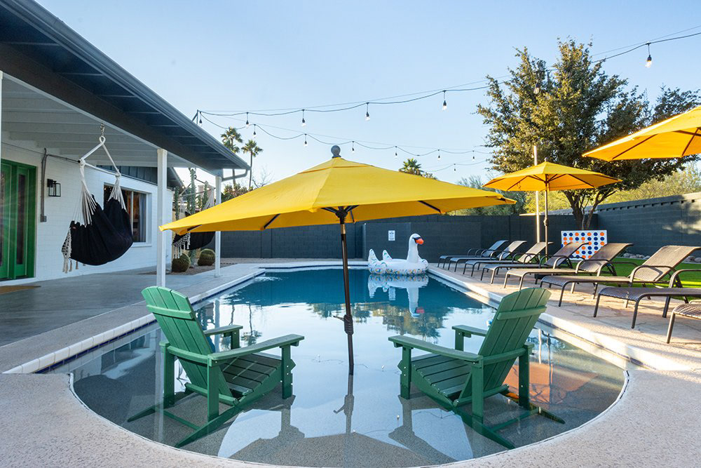 Backyard pool with yellow umbrellas and lounge chairs, vacation rental