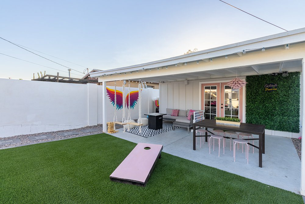 Covered patio and turf yard with cornhole