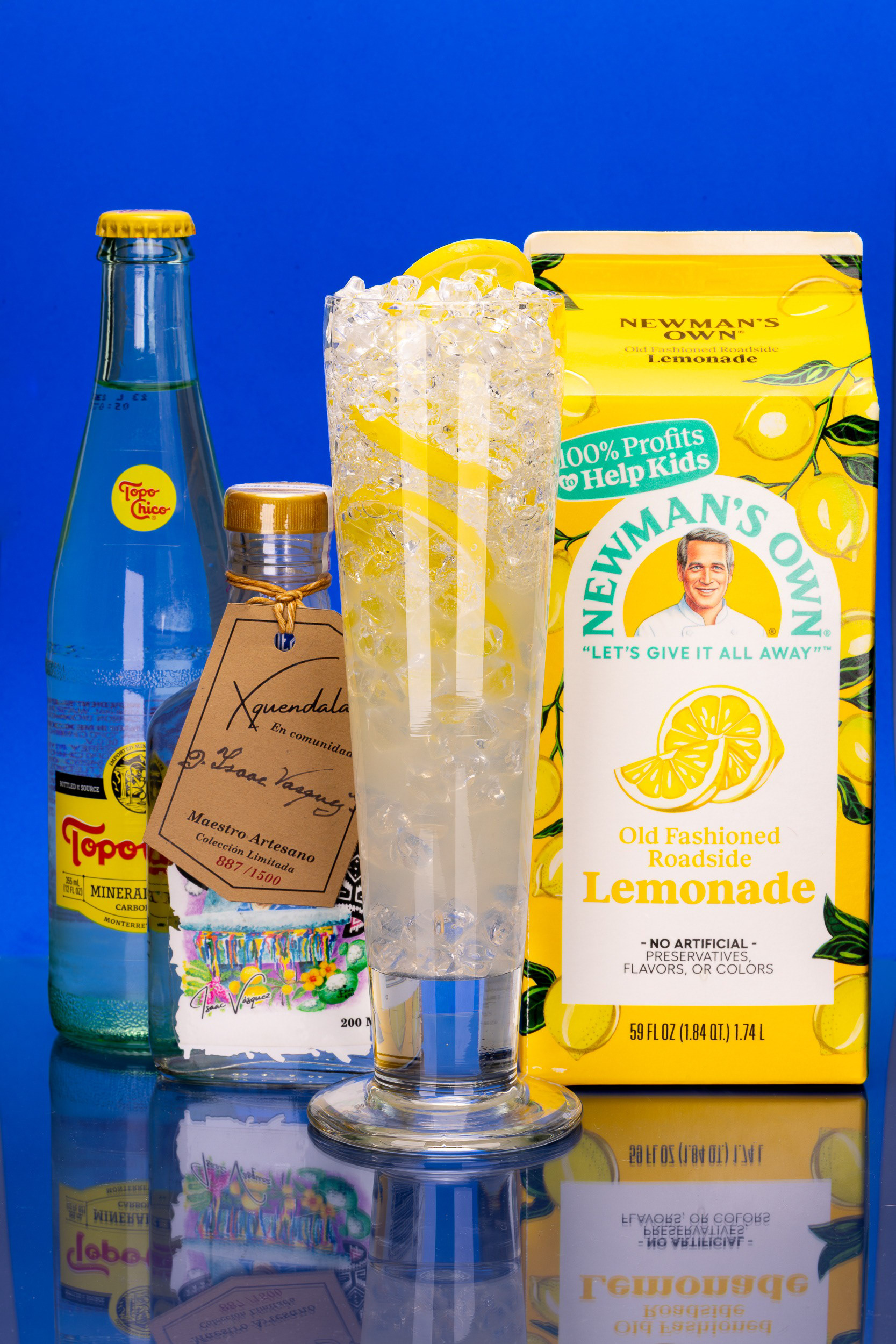 Lemonade cocktail with a mezcal bottle on blue, beverage photography