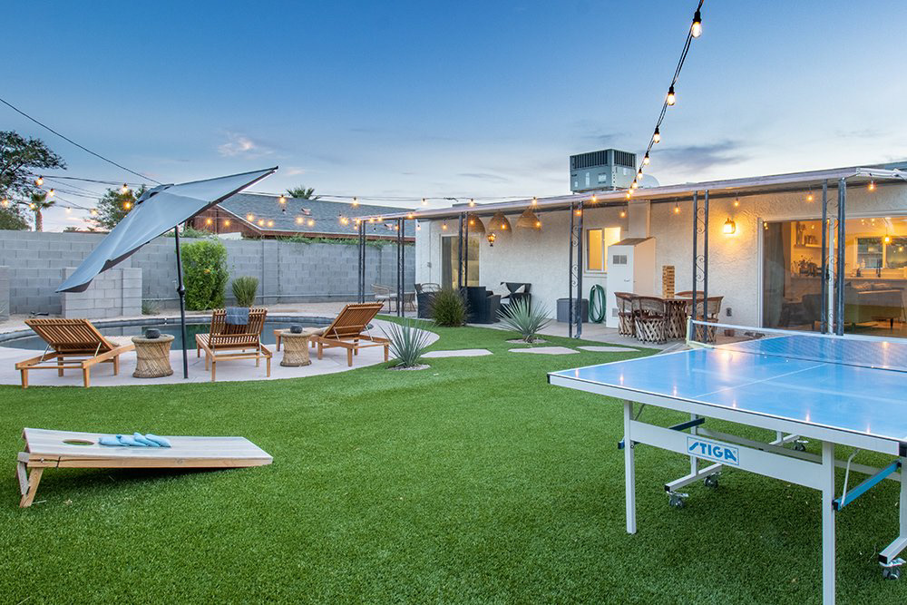Backyard with ping-pong table and cornhole on turf
