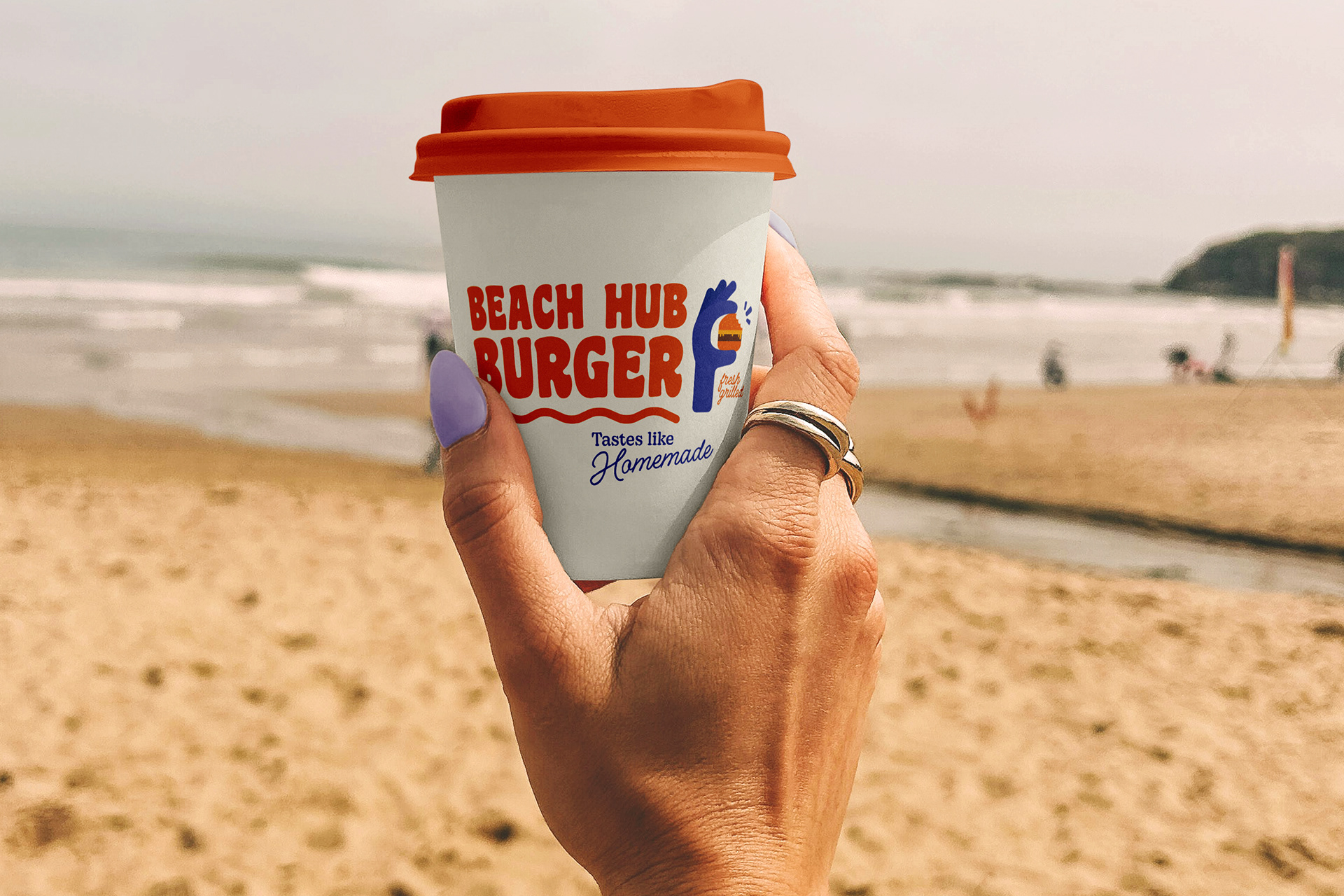 hand holding a cup with the Beach Hub Burger Logo