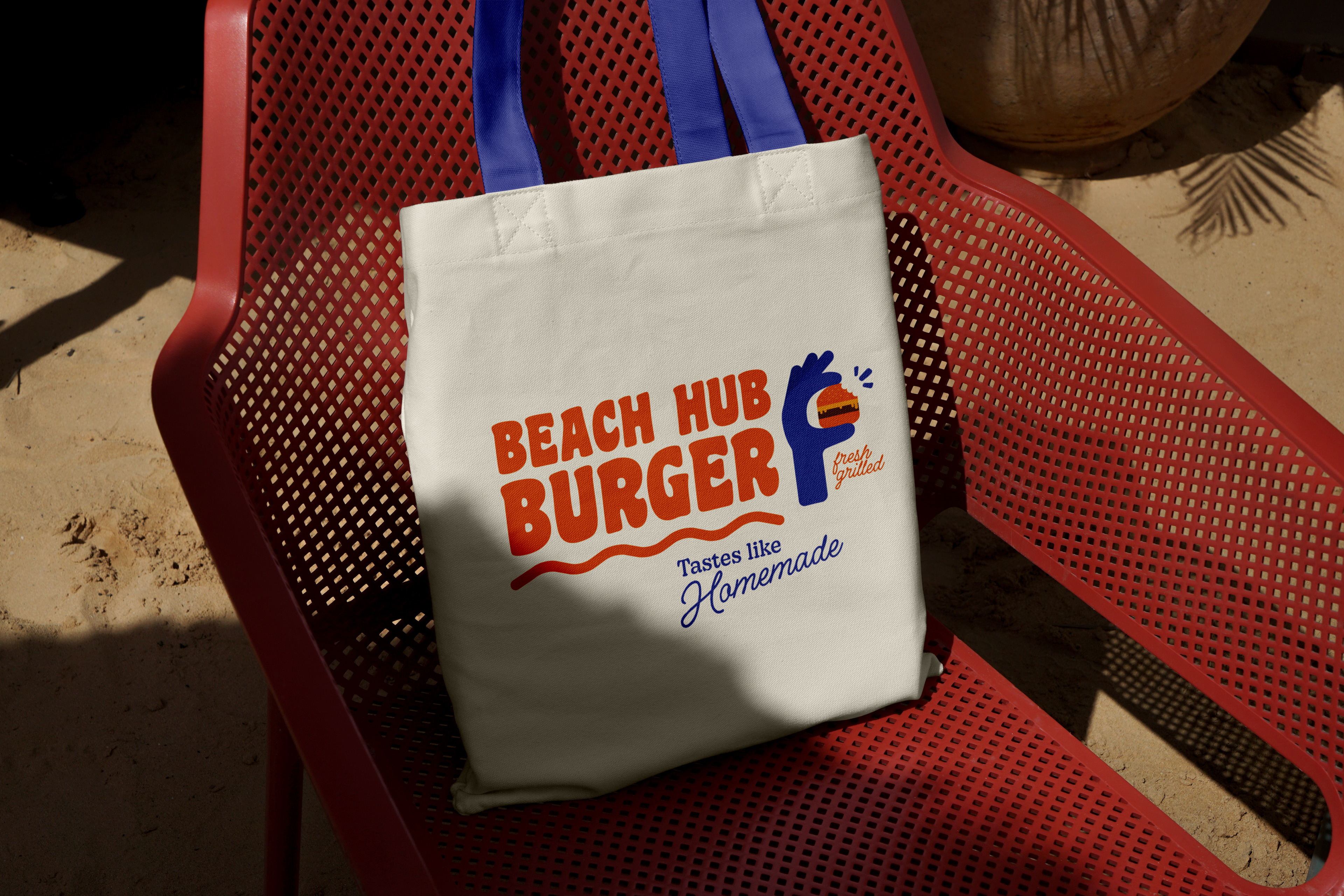 A canvas bag with the restaurant logo lying on a chair on the beach