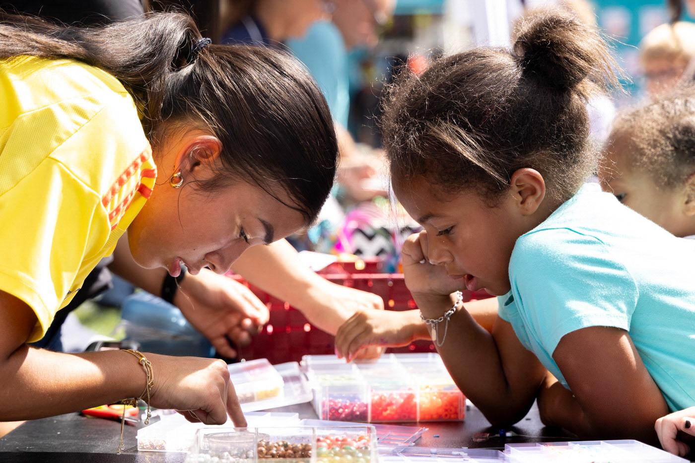 Zamora Cobb, with the help of a Warren County High School volunteer, chooses beads to use to make arts and crafts during the Bowling Green International Festival at Circus Square Park on Saturday, Sept. 27, 2025.