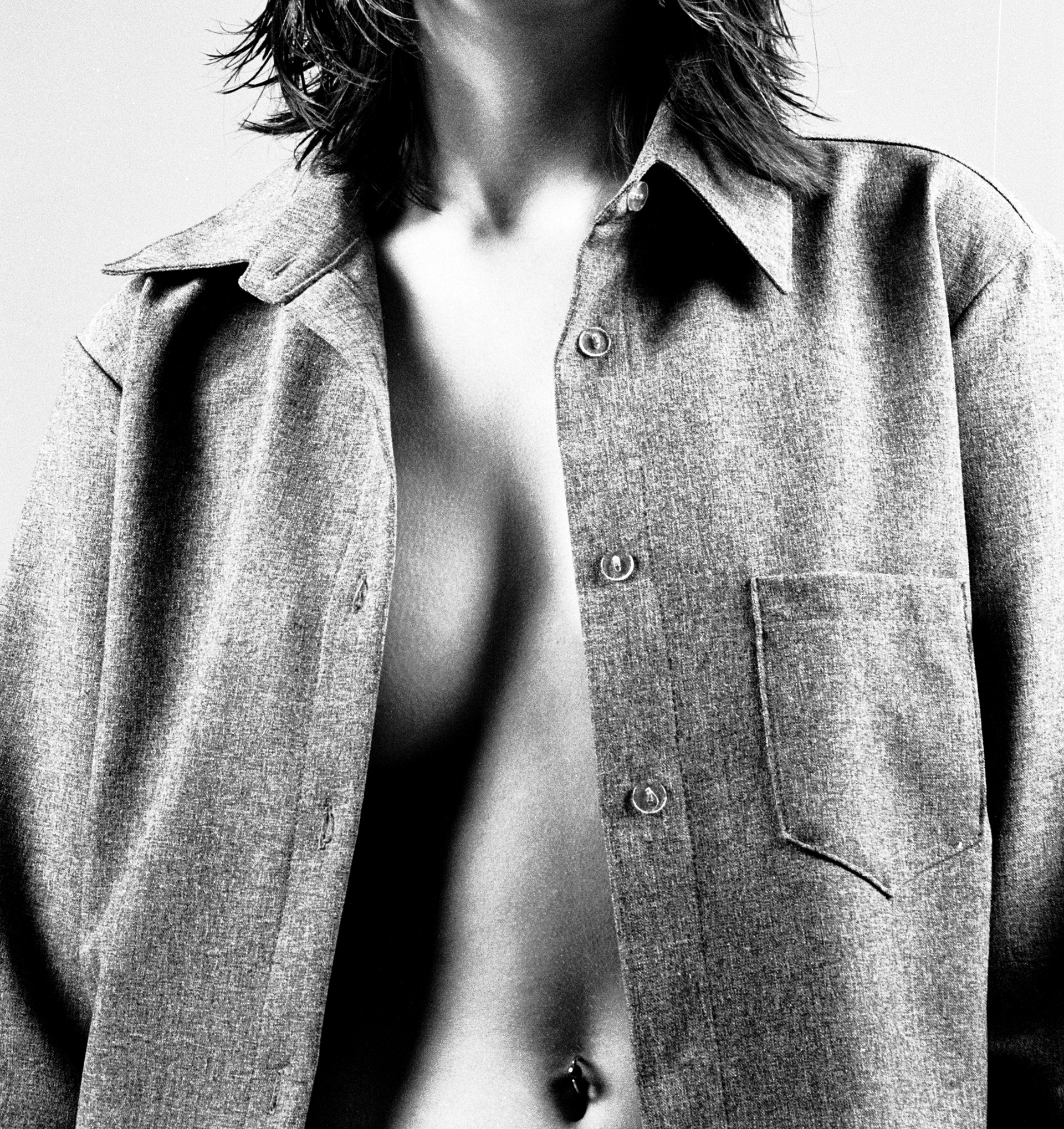 Black and White image of a Brunette Female model wearing an open breast jacket showing belly button-studio image