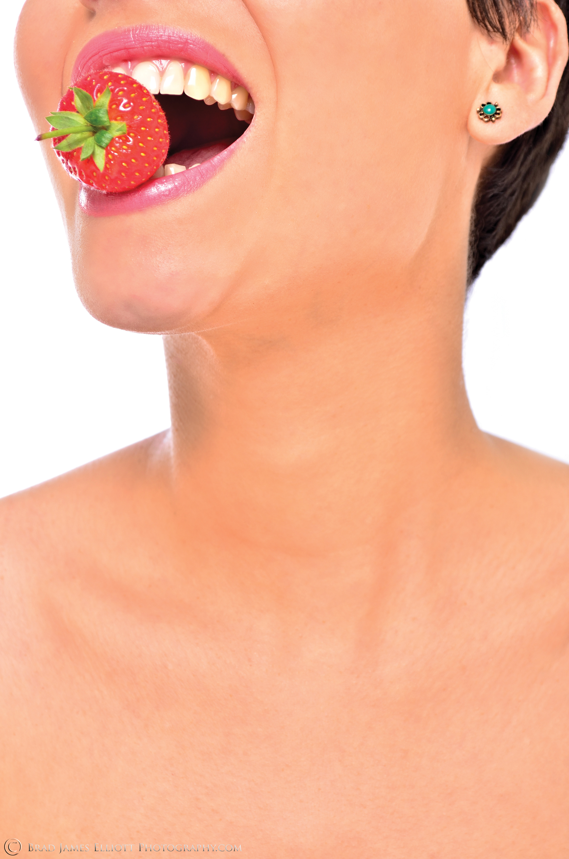 Brunette Female model with strawberry in her mouth-studio image
