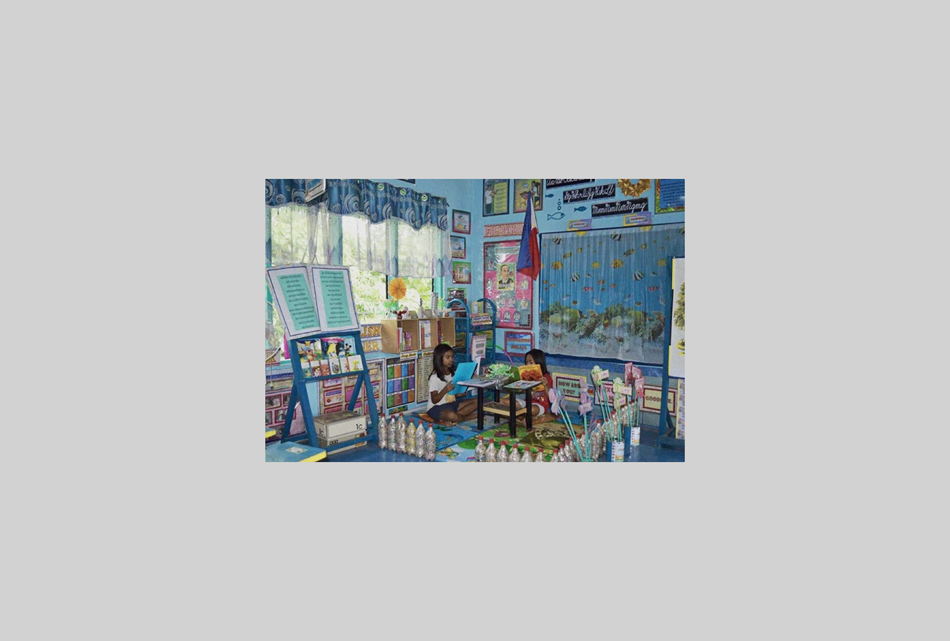 A vibrant Philippine classroom decorated with handmade, marine-themed educational materials, where students read surrounded by colourful charts and ocean imagery.