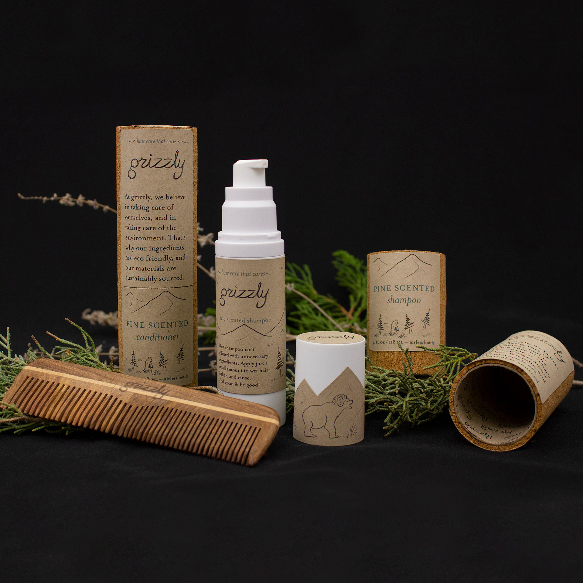 Hero photo of the labelled bottle and labelled cork sleeve with a wooden comb and pine sprigs on a black background.