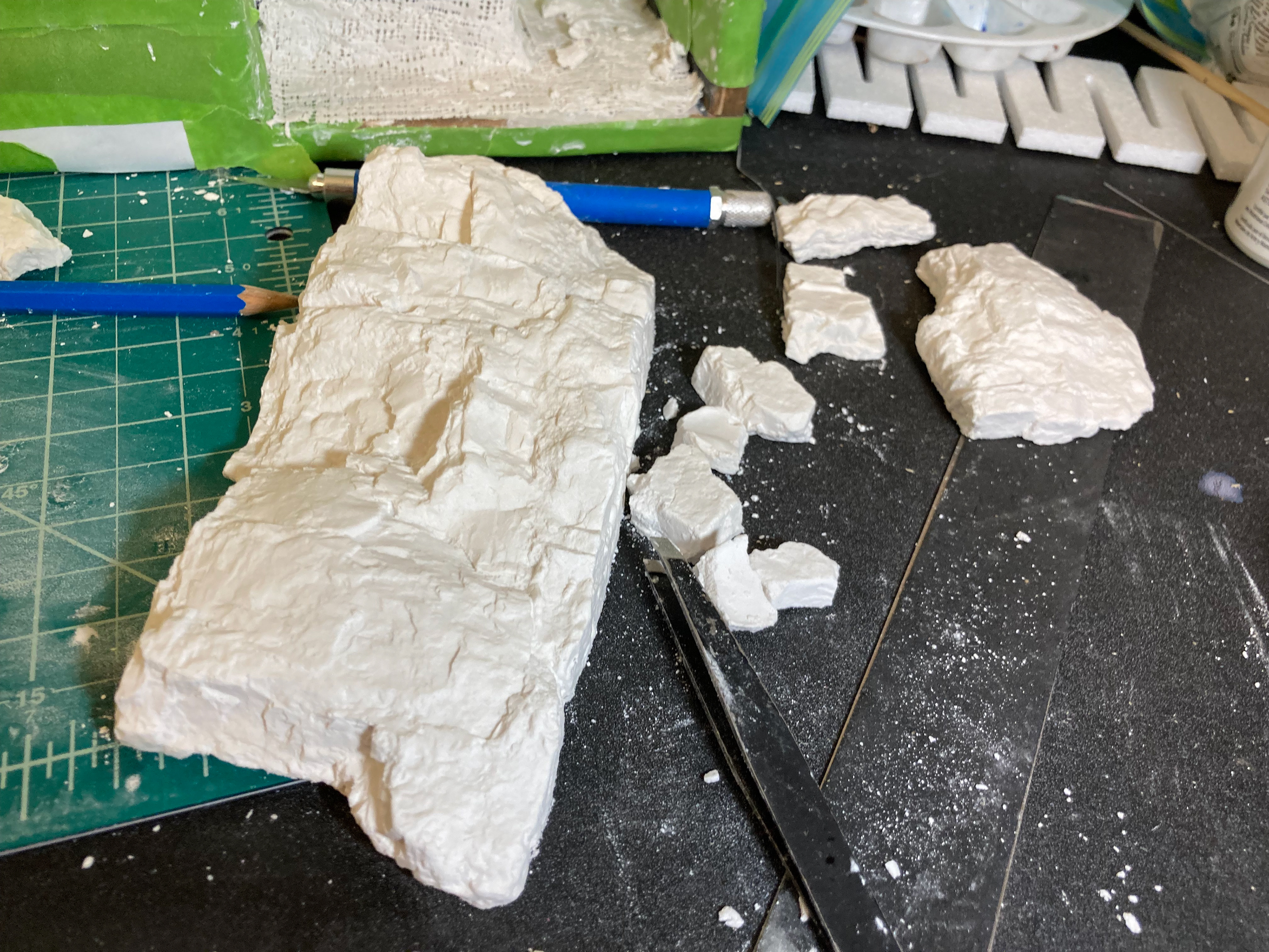 Woodland Scenics makes pricey but reusable rock molds. They look huge, but the key is to break them down smaller by hand. The jagged breaks look completely natural in context.