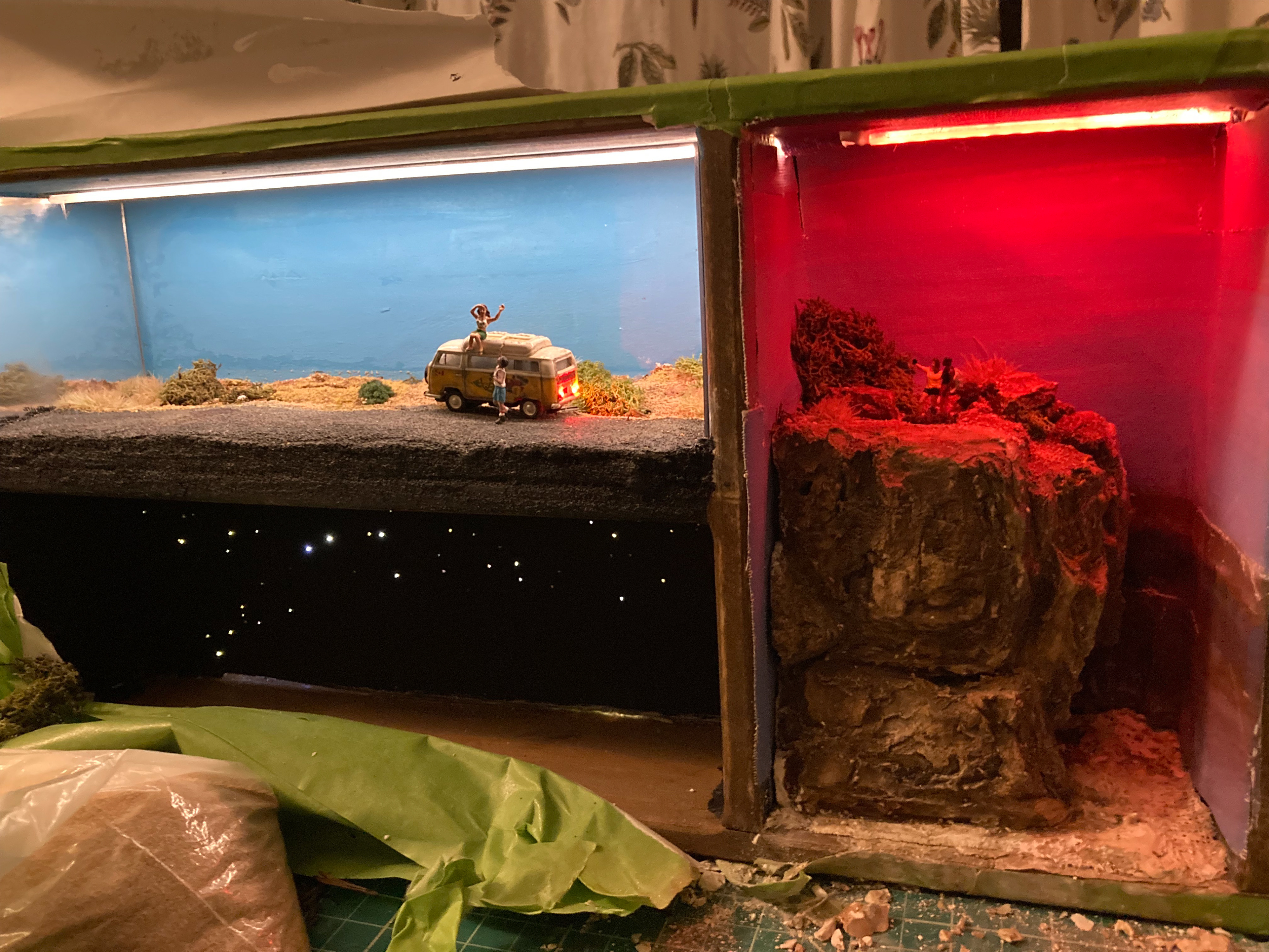 The overhead LED lighting is courtesy of a Home Depot-sourced under-counter lighting kit. I managed to wire this up to the same circuit as the Woodland Scenics system, which is absolutely not something WS wants you to do. But voltage is voltage, and the numbers check out. I tinted the Grand Canyon scene to be sunsetty using red cellophane over the strip.