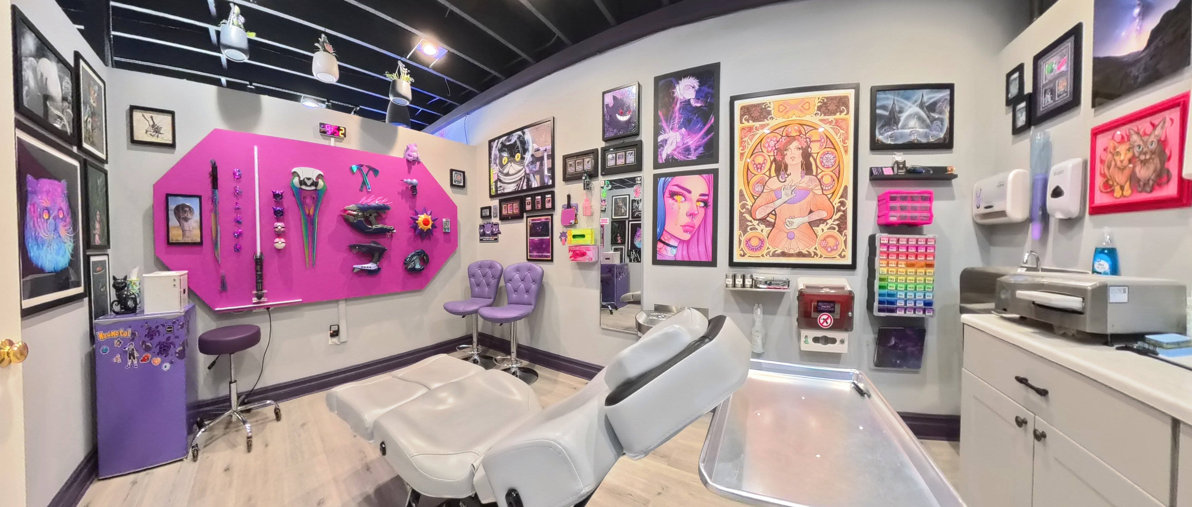 Studio treatment room with an adjustable chair, framed artwork and purple wall accents.