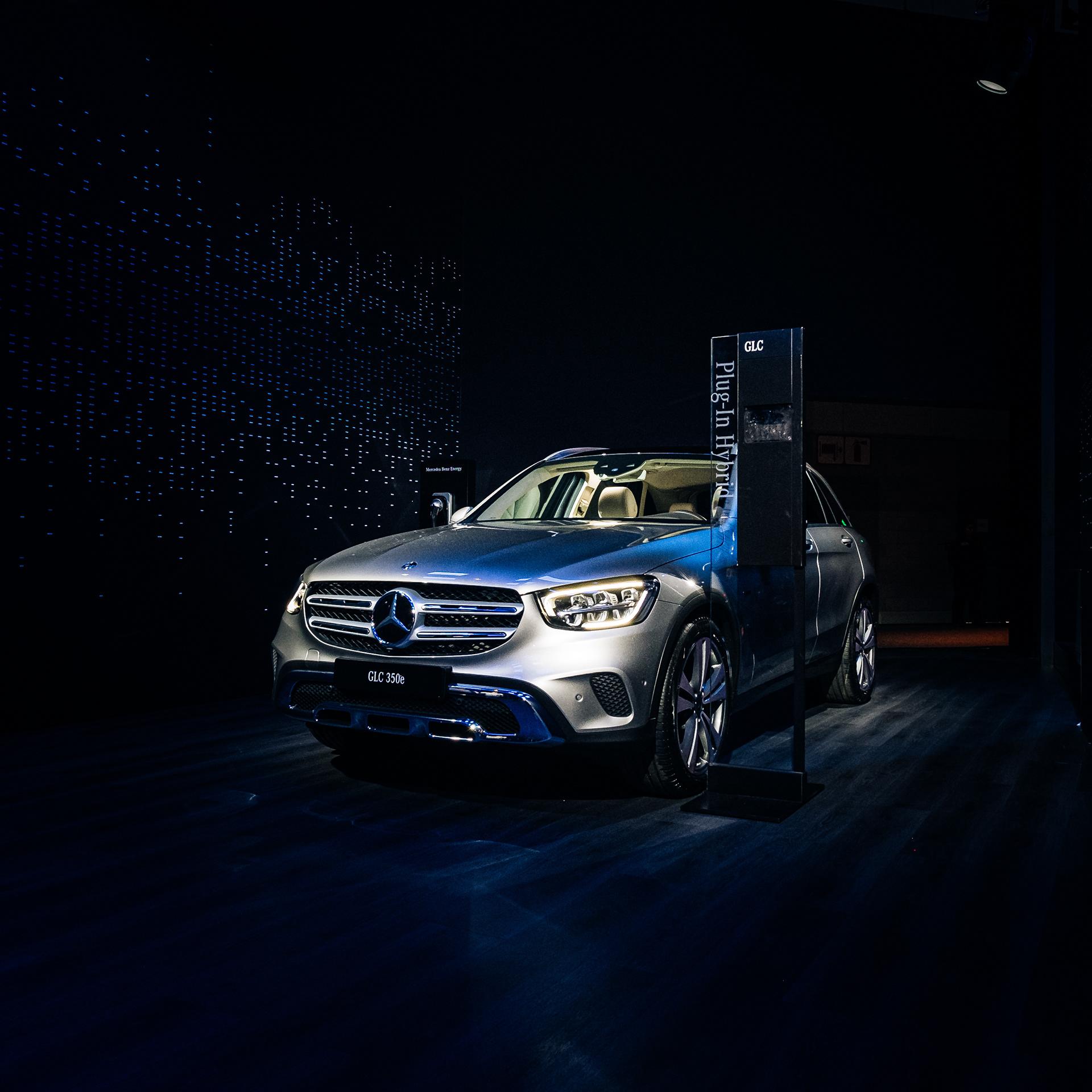 Silver Mercedes-Benz SUV displayed under spotlights at an indoor auto show.