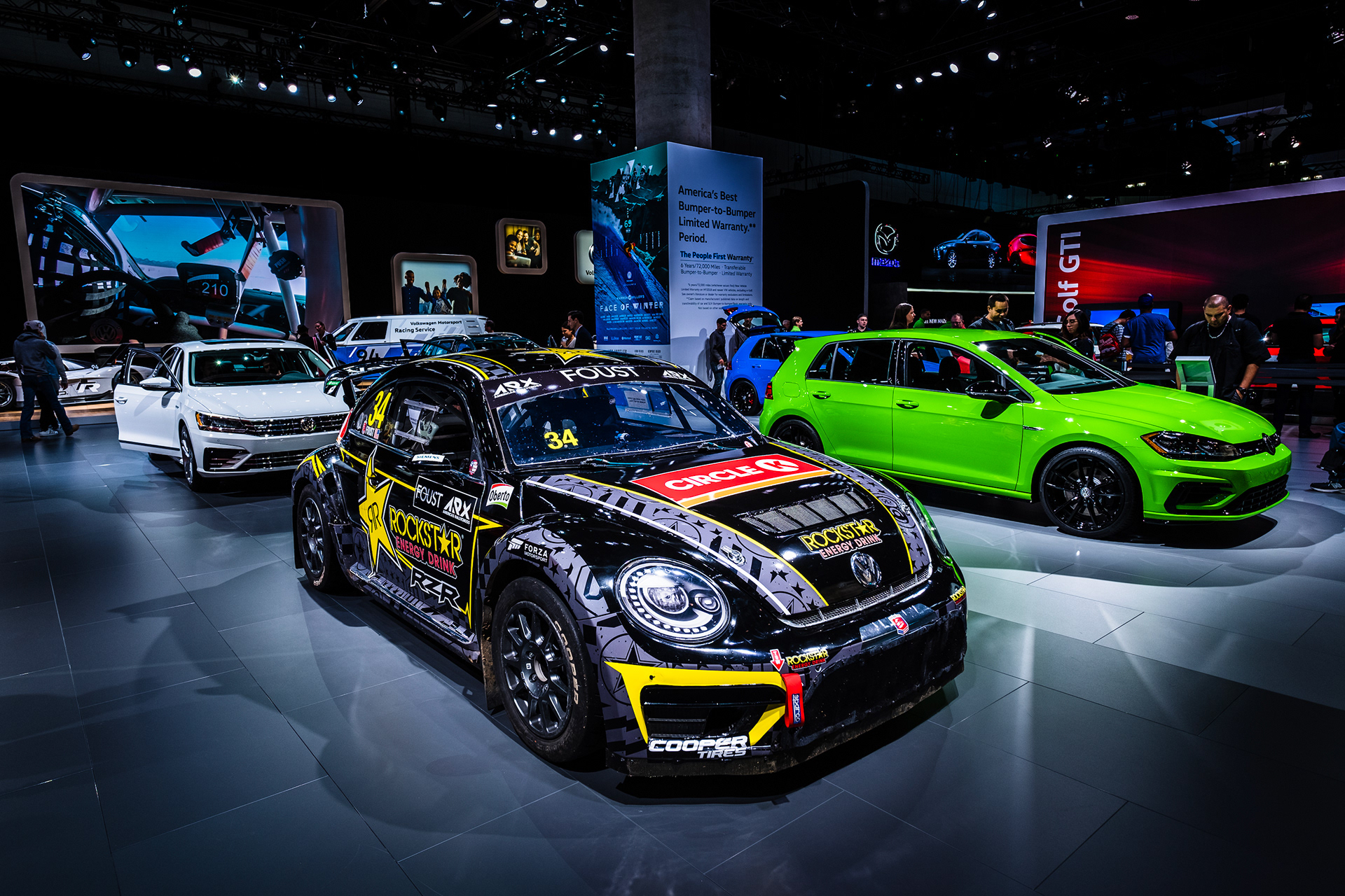 Volkswagen Beetle race car with black and yellow graphics on an auto show display.