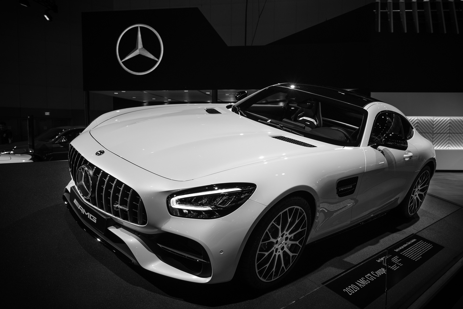Black-and-white photograph of a white Mercedes-AMG sports car on display.