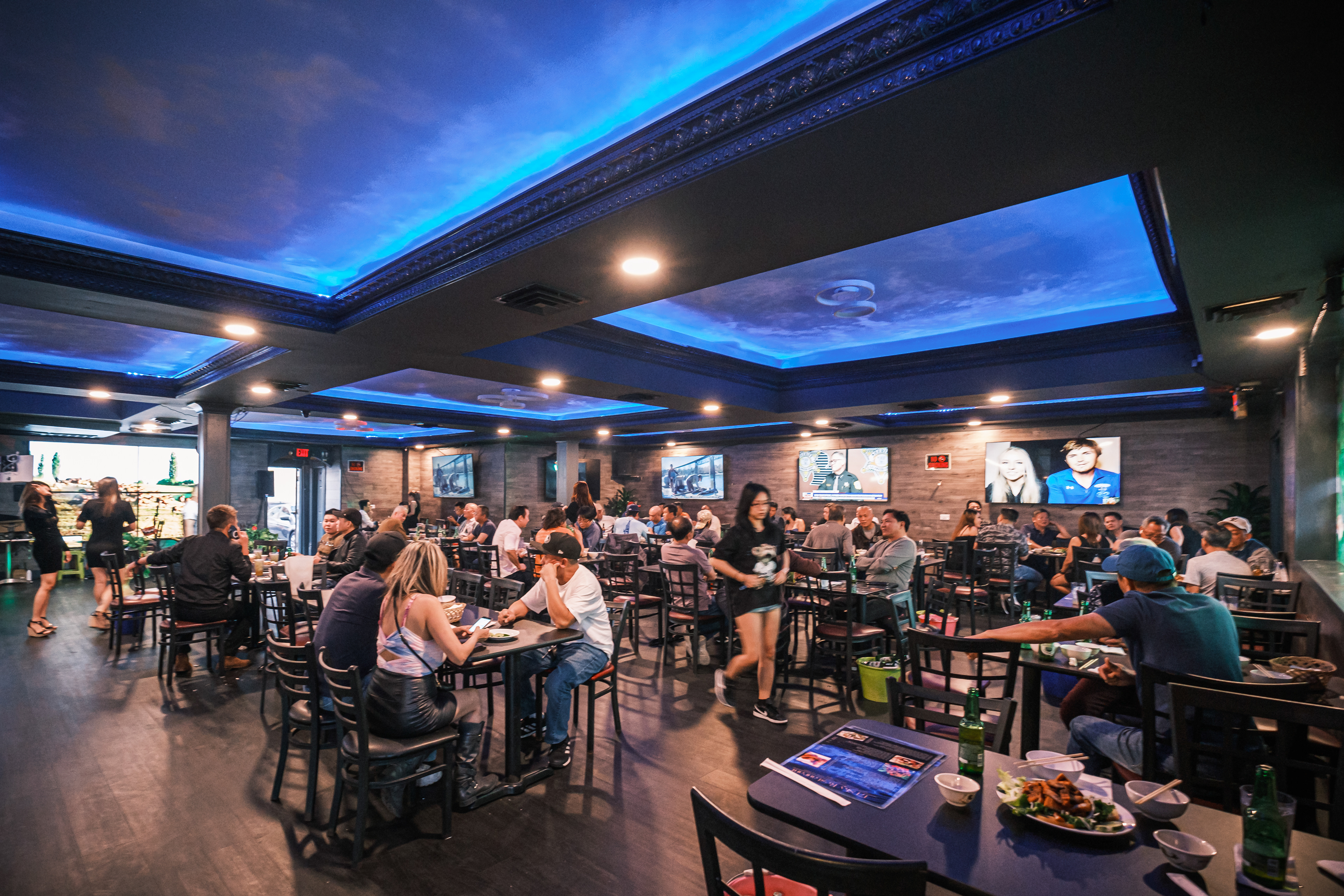 Restaurant dining room with blue ceiling lighting and guests seated at tables