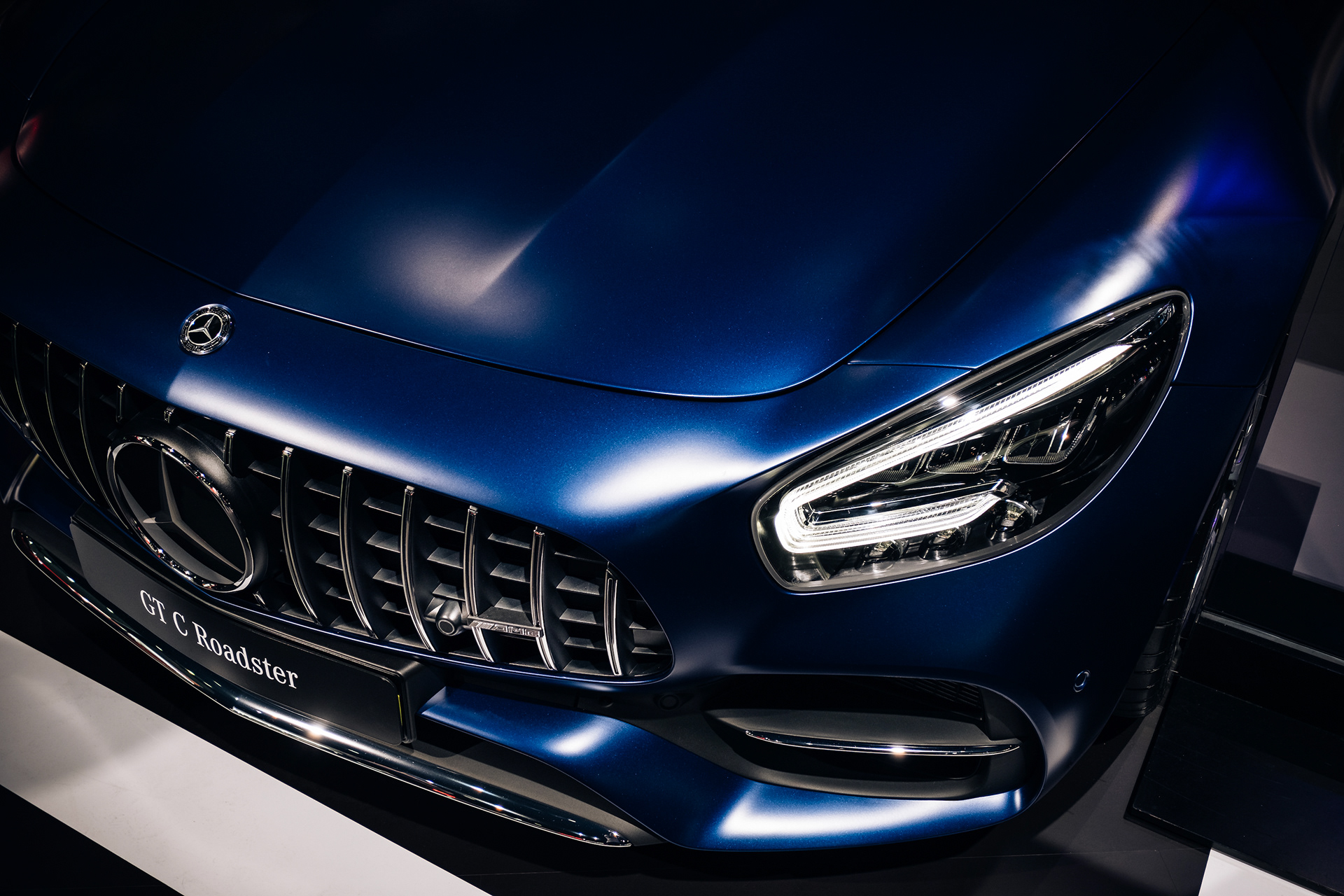 Close-up of the grille and headlight on a blue Mercedes-AMG GT C Roadster.