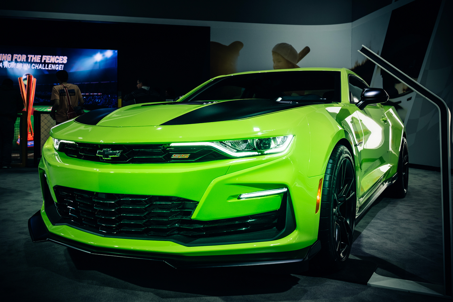 Bright green Chevrolet Camaro photographed from the front at an indoor auto show.