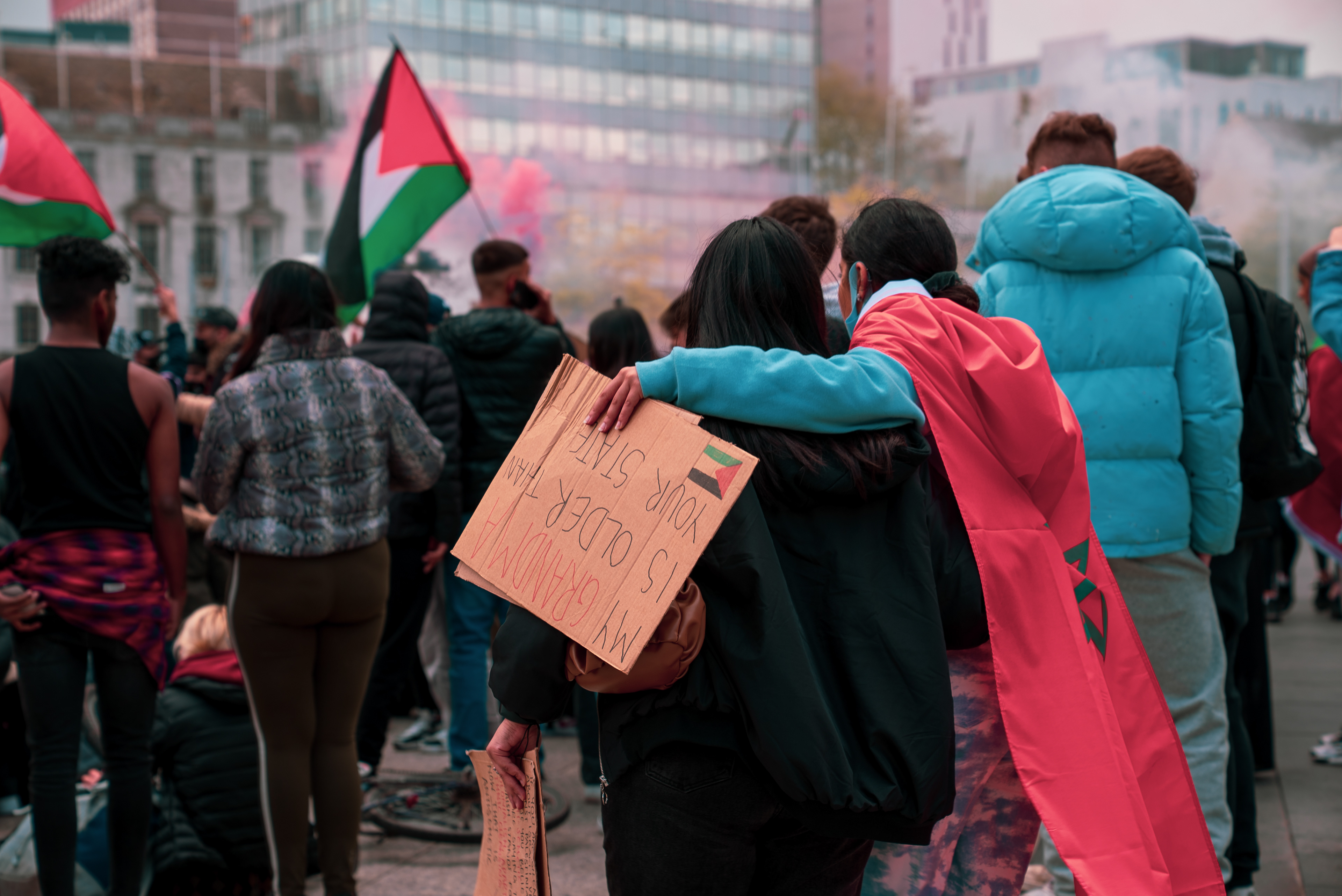 The woman in the cape puts her arm around a fellow protestor